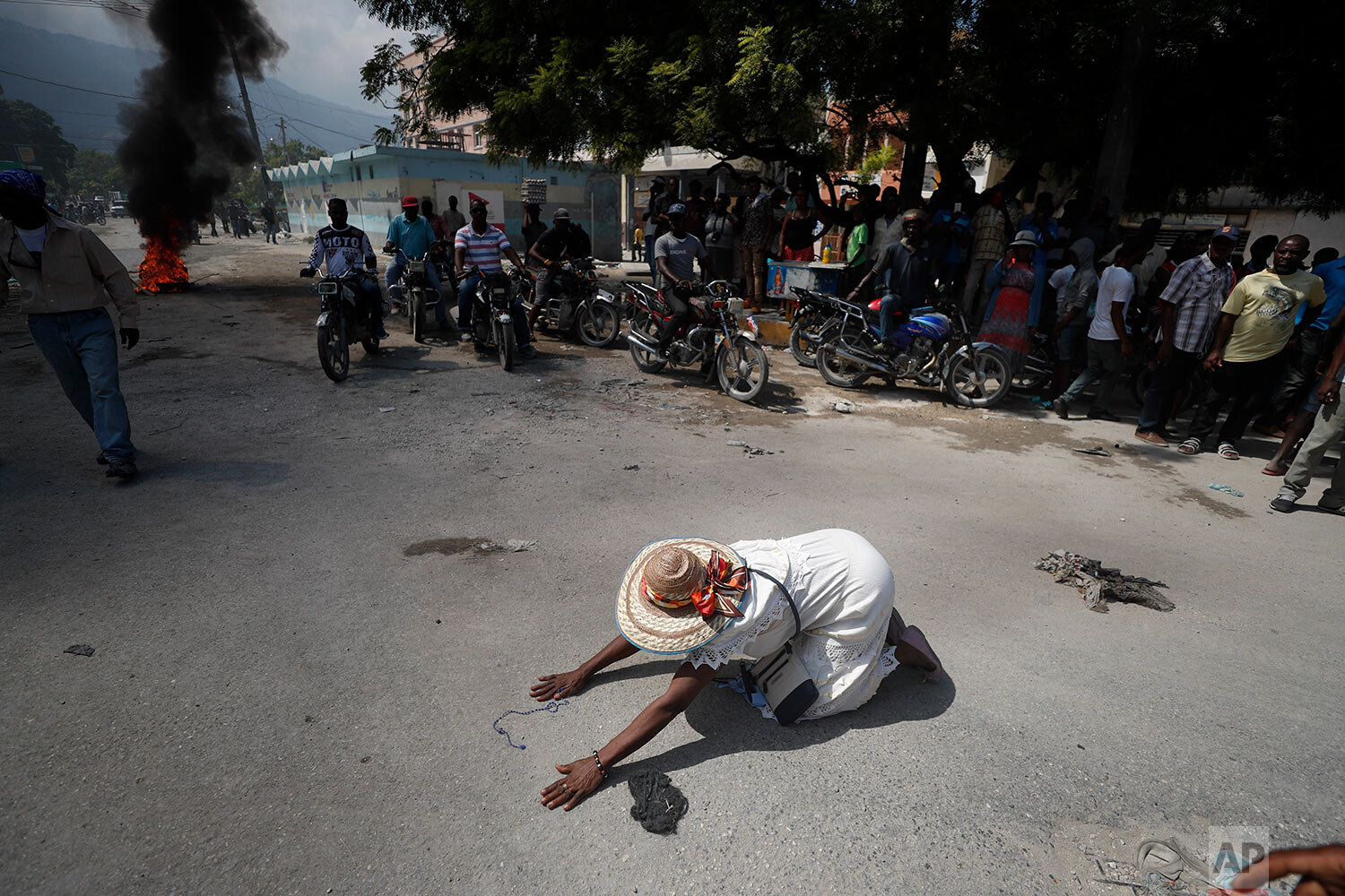  A churchgoer drops to the ground and prays in the street near burning tires lit by protesters, during a march called by religious leaders in Port-au-Prince, Haiti, on Oct. 22, 2019. (AP Photo/Rebecca Blackwell) 