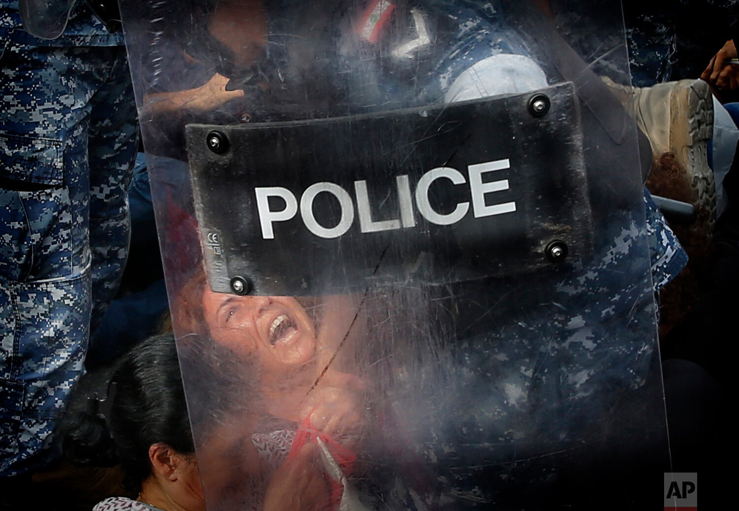  A riot policeman removes an anti-government protester who is blocking a main highway with her body in Beirut, Lebanon, on Oct. 26, 2019. (AP Photo/Hussein Malla) 