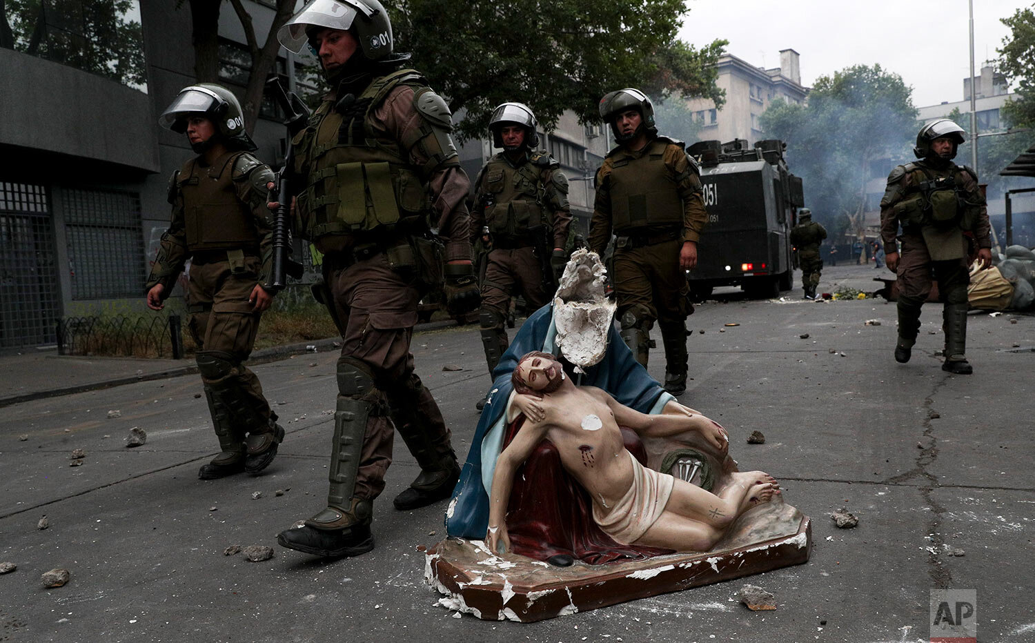  Police advance on anti-government protesters, past a religious statue that protesters removed from a church and then damaged, in Santiago, Chile, on Nov. 8, 2019. (AP Photo/Esteban Felix) 