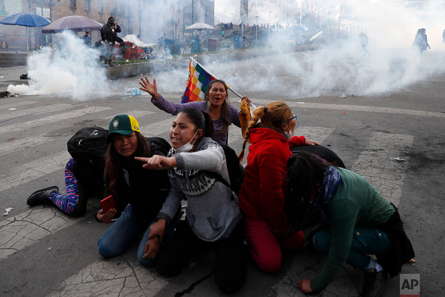  Supporters of former President Evo Morales protect themselves from tear gas launched by the police in La Paz, Bolivia, on Nov. 15, 2019. (AP Photo/Natacha Pisarenko) 