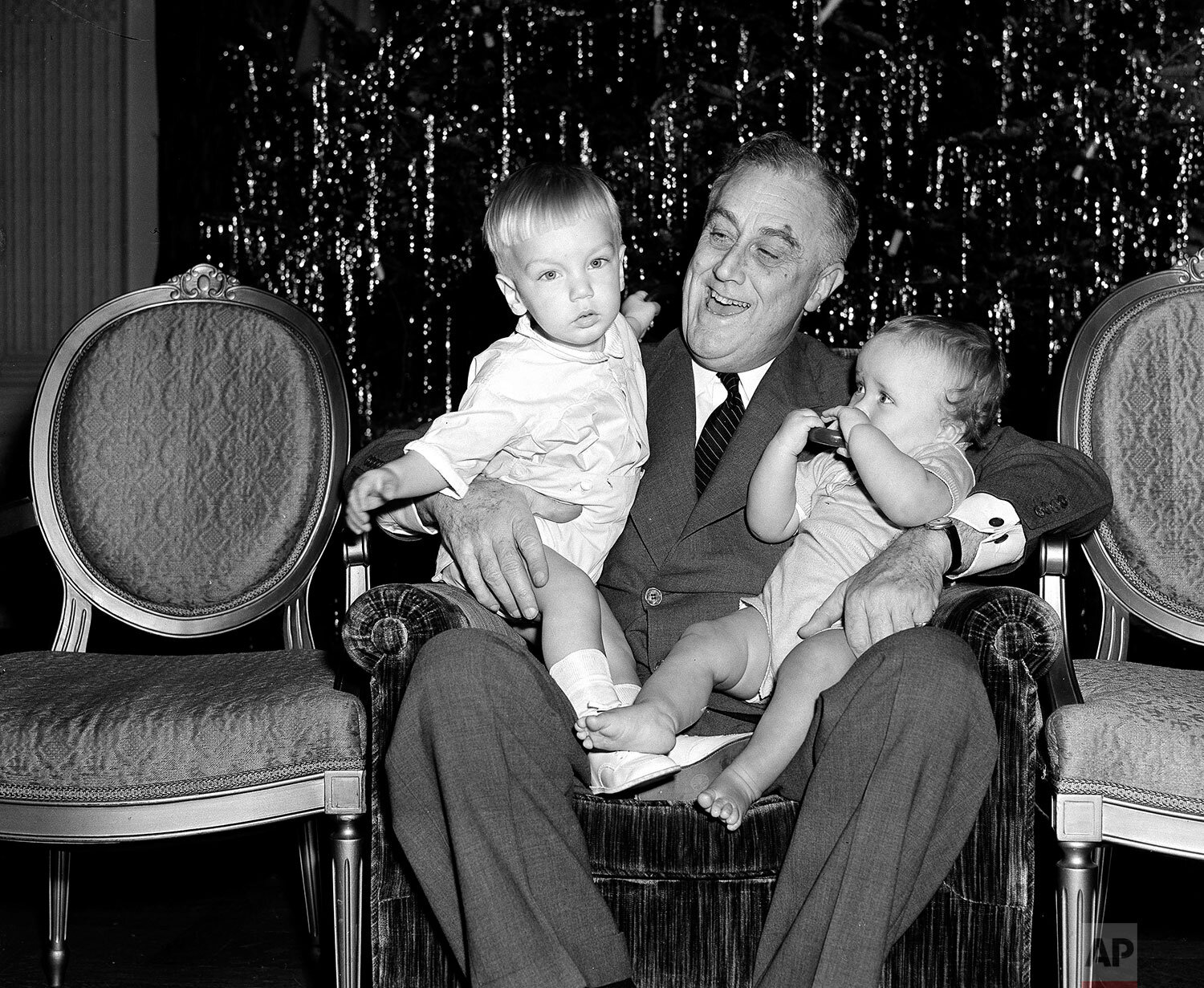  President Franklin D. Roosevelt holds two of his grandchildren on Christmas Day, Dec. 25, 1939, in the East Room of the White House in Washington. At left is Franklin Roosevelt III, son of FDR Jr., and Johnny Boettiger, nine-month-old son of the pre