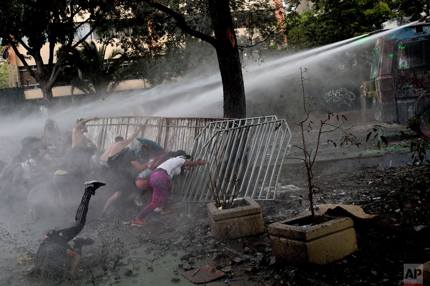  Anti-government protesters are sprayed by a police water cannon during clashes in Santiago, Chile, Friday, Nov. 29, 2019. (AP Photo/Esteban Felix) 