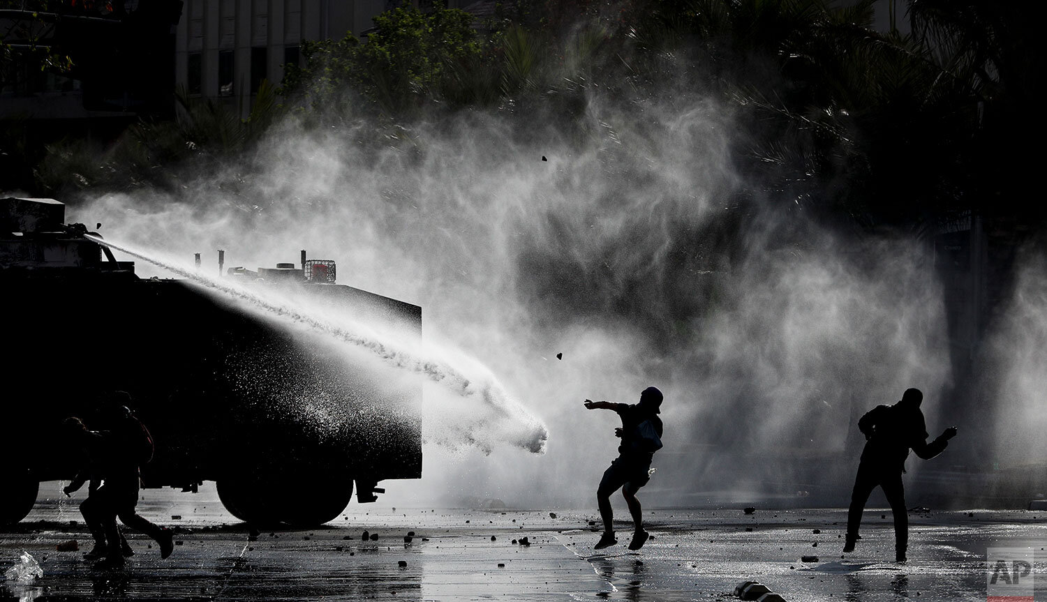  Demonstrators clash with a police water cannon during an anti-government protest in Santiago, Tuesday, Nov. 5, 2019. Chileans have been taking to the streets and clashing with the police to demand better social services and an end to economic inequa