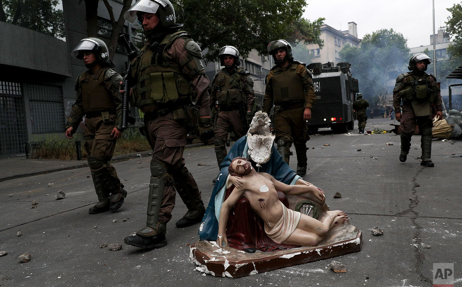  Police advance on anti-government protesters, past a religious statue that protesters removed from a church and then damaged, in Santiago, Chile, Friday, Nov. 8, 2019. Chile's president on Thursday announced measures to increase security and toughen