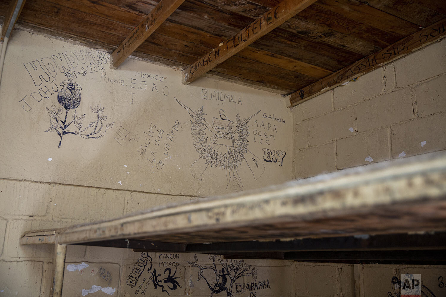  In this Nov. 1, 2019 photo, graffiti by Central American migrants depicting the Guatemalan coat of arms, the word Honduras and migrants' names cover the wall of a room inside a stash house known as a guest house, in Altar, Sonora state, Mexico. (AP 