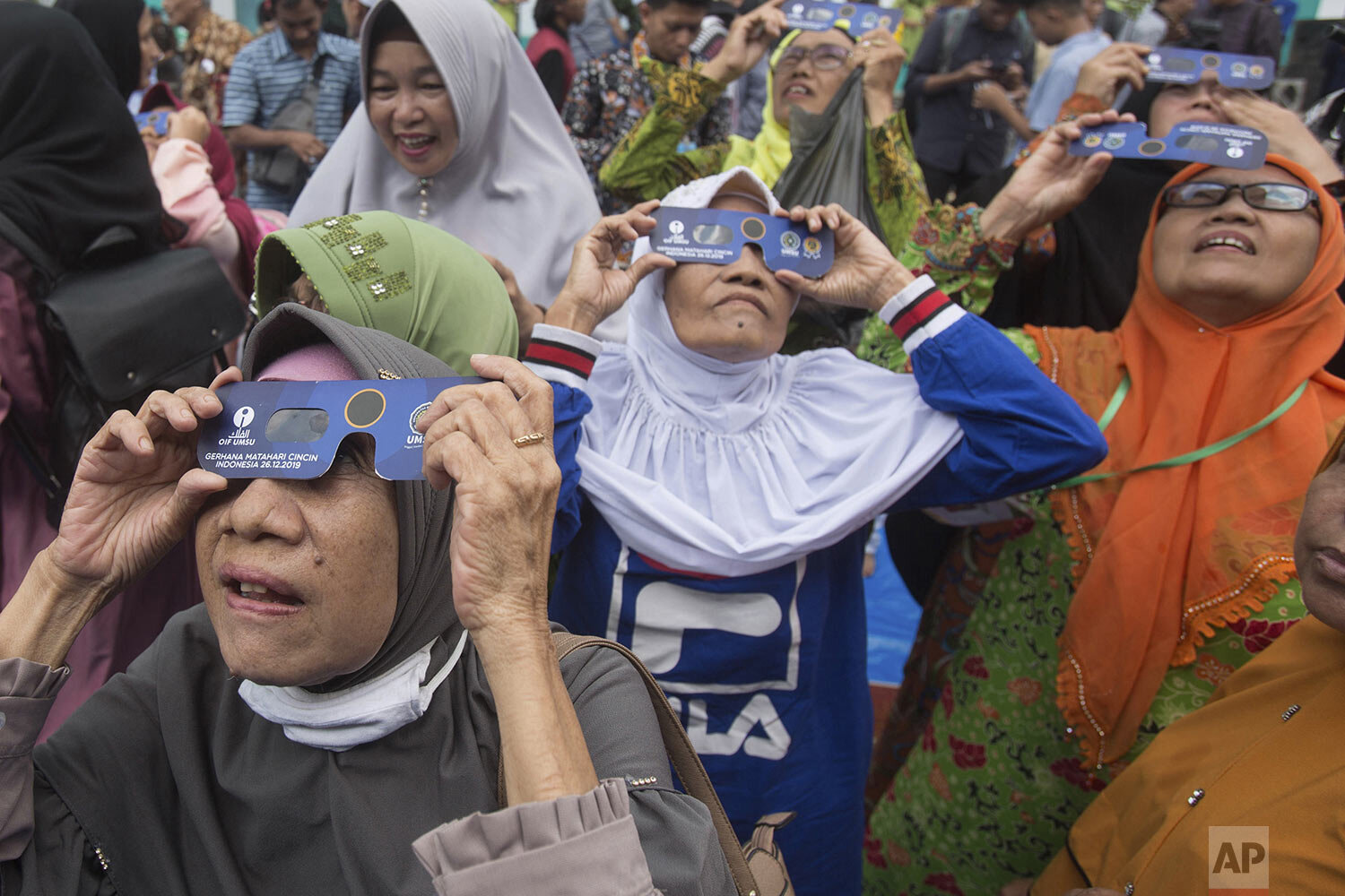  Muslim women watch a solar eclipse through special glasses at the campus of the Faculty of Astronomy of Muhammadiah University of North Sumatra (UMSU) in Medan, Indonesia, Thursday, Dec. 26, 2019. (AP Photo/Binsar Bakkara) 