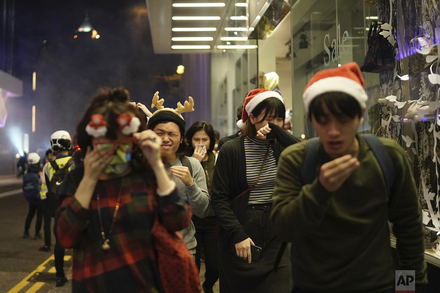  Residents dressed for Christmas festivities react to tear gas as police confront protesters on Christmas Eve in Hong Kong on Tuesday, Dec. 24, 2019. (AP Photo/Kin Cheung) 