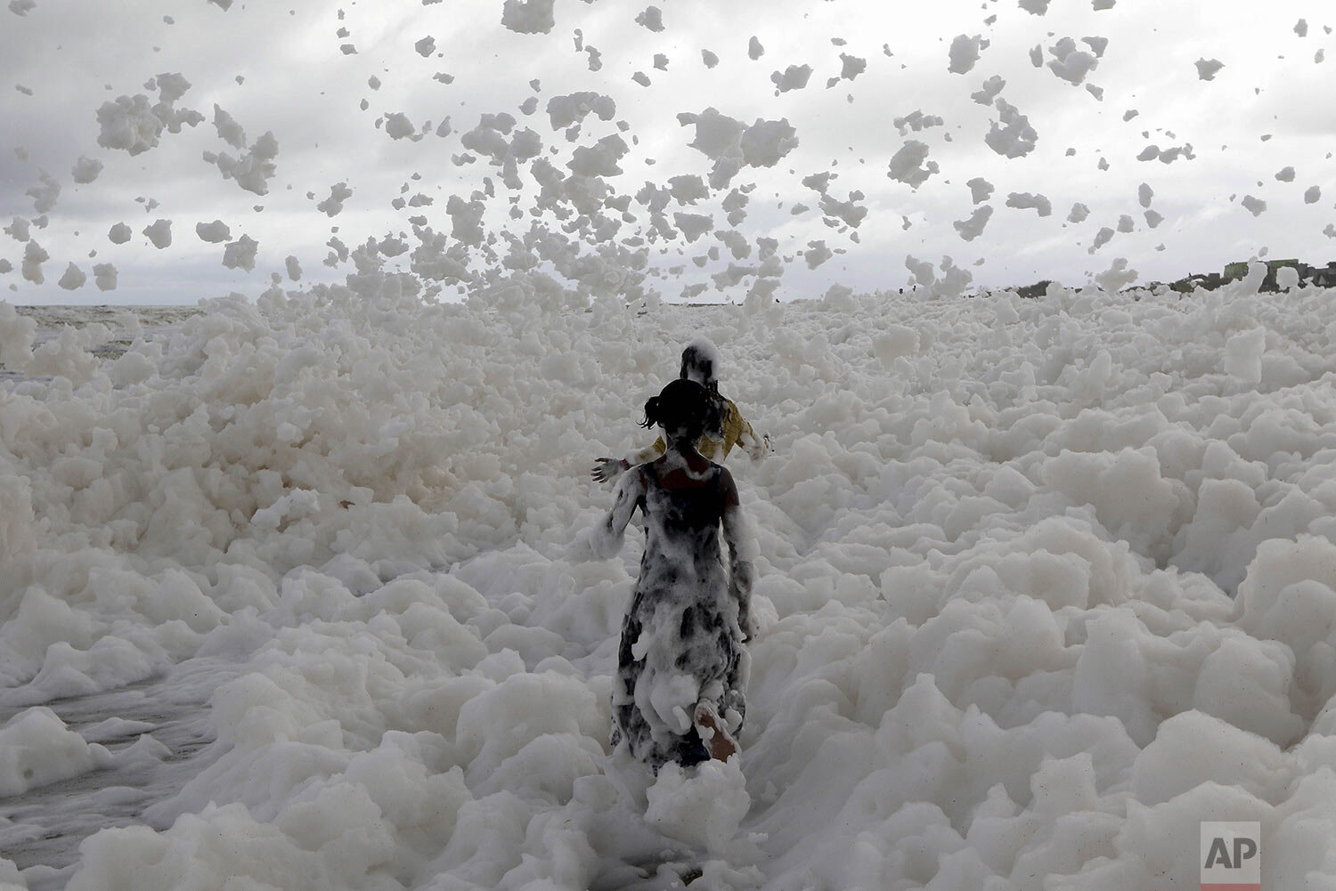  Children play on the Marina beach on the Bay of Bengal coast which is blanketed in sea foam in Chennai, India, Sunday, Dec. 1, 2019. (AP Photo/R.Parthibhan) 