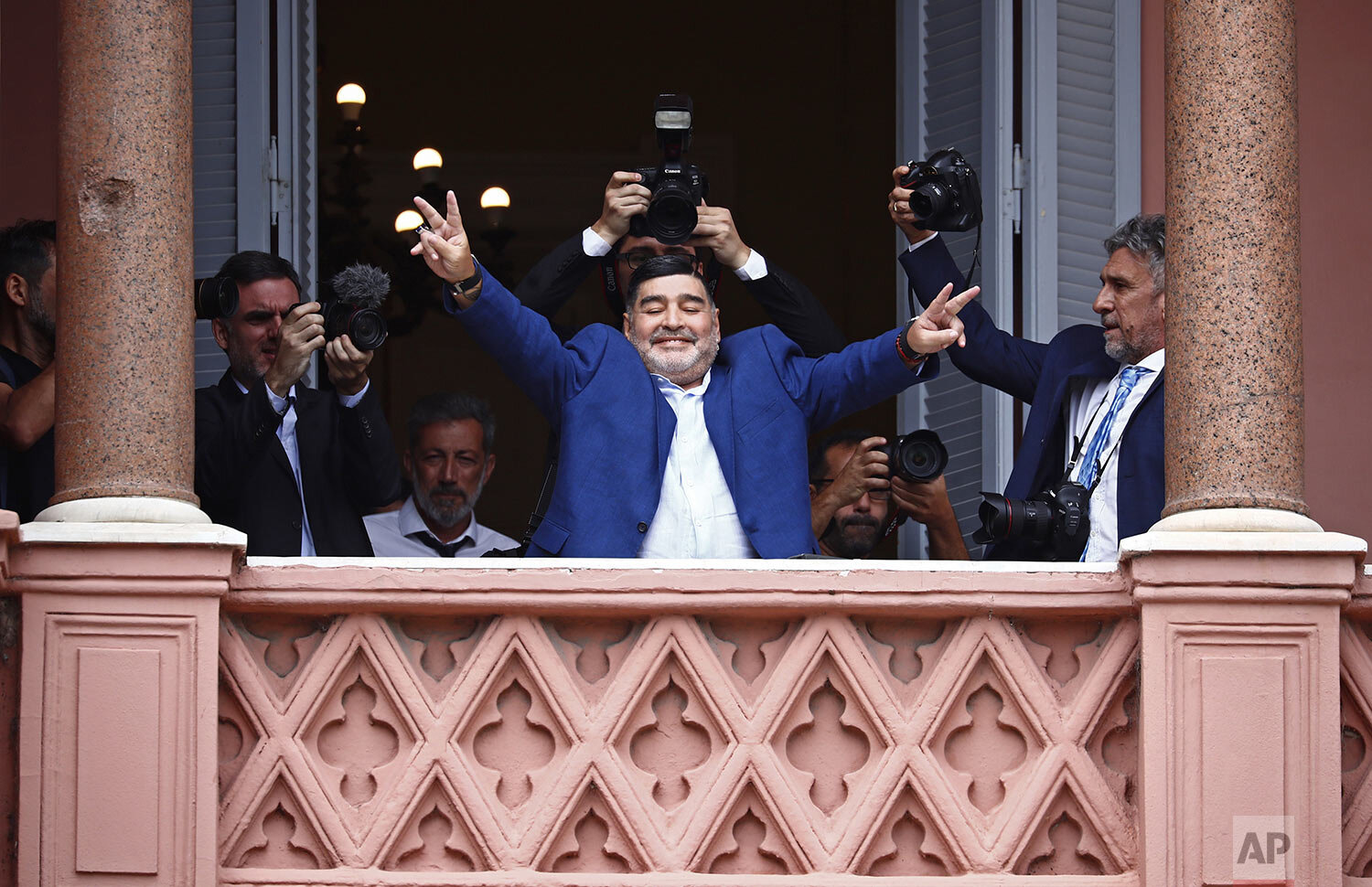  Former soccer great Diego Maradona flashes victory signs to fans below at the Casa Rosada government house after meeting with Argentine President Alberto Fernandez in Buenos Aires, Argentina, Dec. 26, 2019. Decades ago, Maradona held up his team's s