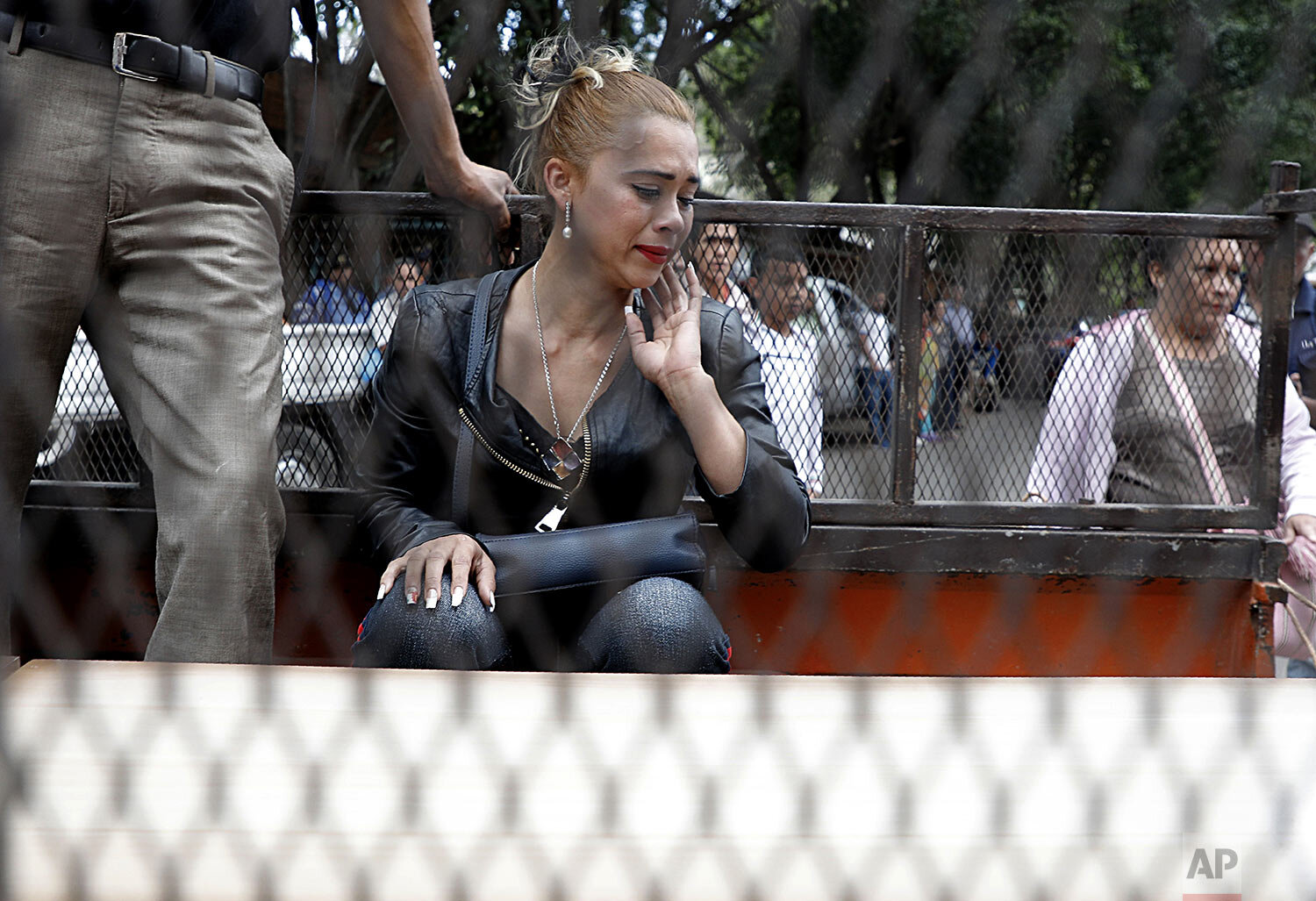  A woman sits behind the coffin of Mario Pavon, one of the prisoners who died the previous day during a riot inside El Porvenir prison, as his remains are carried away by family members in a truck after claiming the body at the morgue in Tegucigalpa,