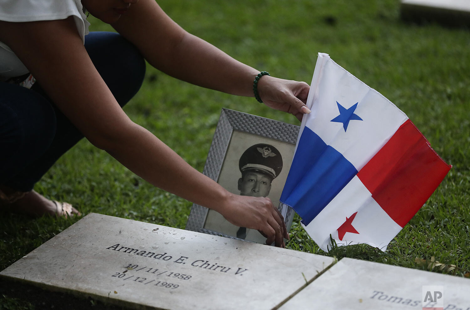  A woman places a Panamanian flag on the grave of a military man who died during the 1989 U.S. military invasion that ousted Panama's strongman Manuel Noriega, on the 30th anniversary of the invasion in Panama City, Dec. 20, 2019. According to offici
