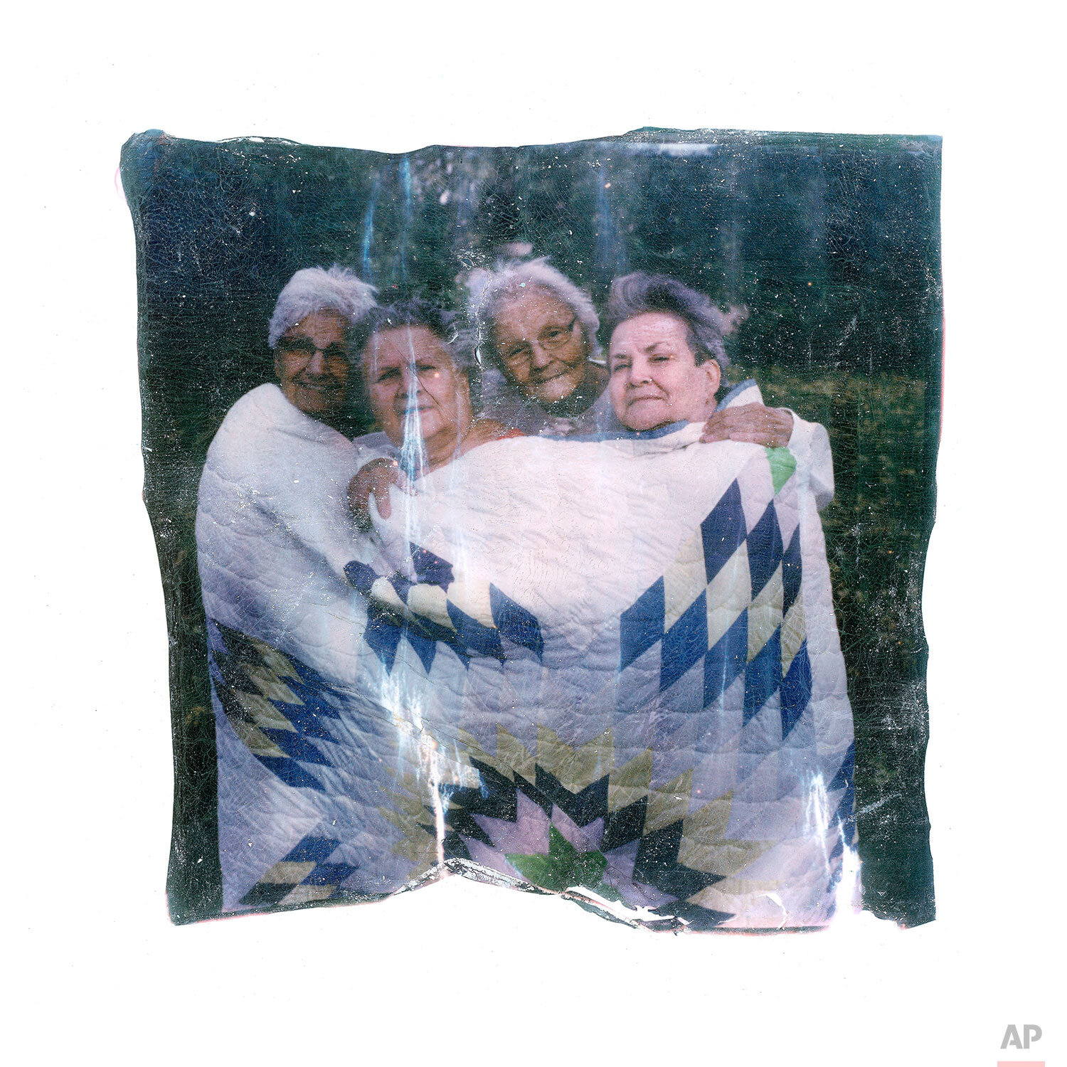  In this image made from a Polaroid emulsion transfer, the Charbonneau sisters, from left to right, Francine Soli, 71, Barbara Dahlen, 67, Joann Braget, 78, and Louis Aamot, 69, pose in a quilt made by their mother, in Walhalla, ND., on Tuesday, Oct.
