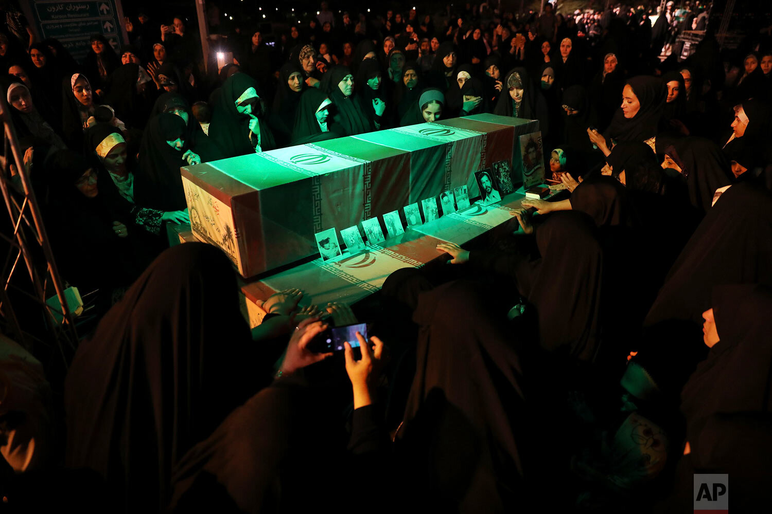  Women mourn over the flag-draped coffins of soldiers who were killed during the 1980-88 Iran-Iraq war, whose remains were recently recovered in the battlefields, during a ceremony prior to funeral for 150 soldiers, mostly unknown, Wednesday, June 26