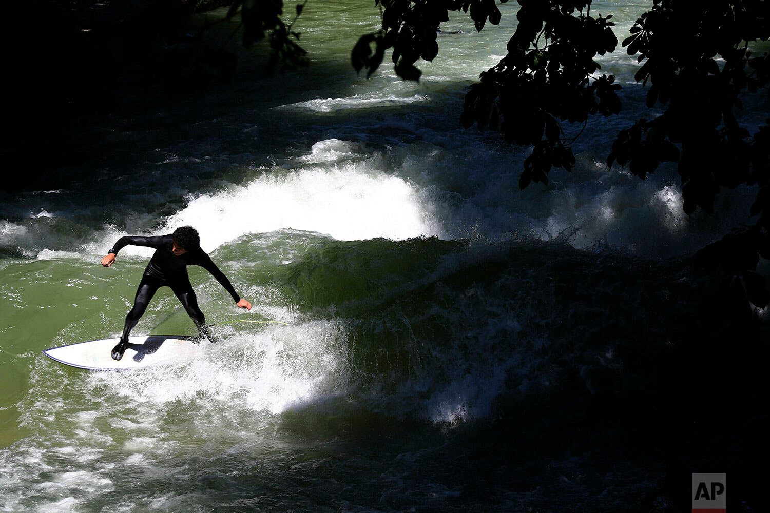  A surfer rides an artificial wave in the river "Eisbach" at the English Garden downtown in Munich, Germany, Monday, June 24, 2019. (AP Photo/Matthias Schrader) 