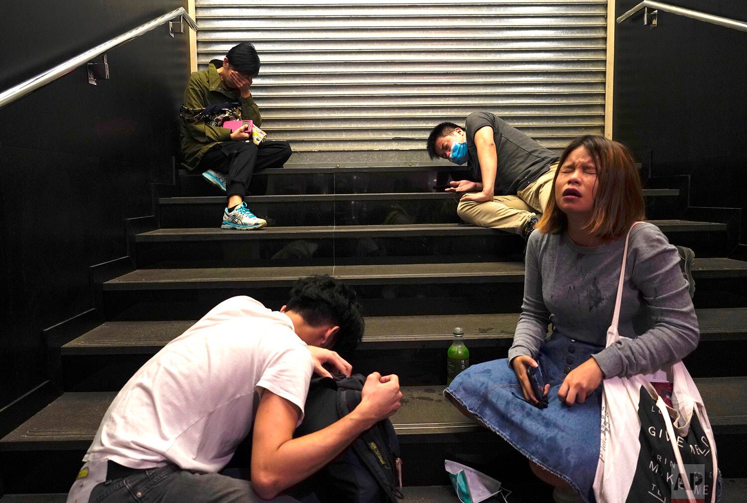  People affected by tear gas sit on steps to recover in the Central district of Hong Kong on Monday, Nov. 11, 2019. (AP Photo/Vincent Yu) 