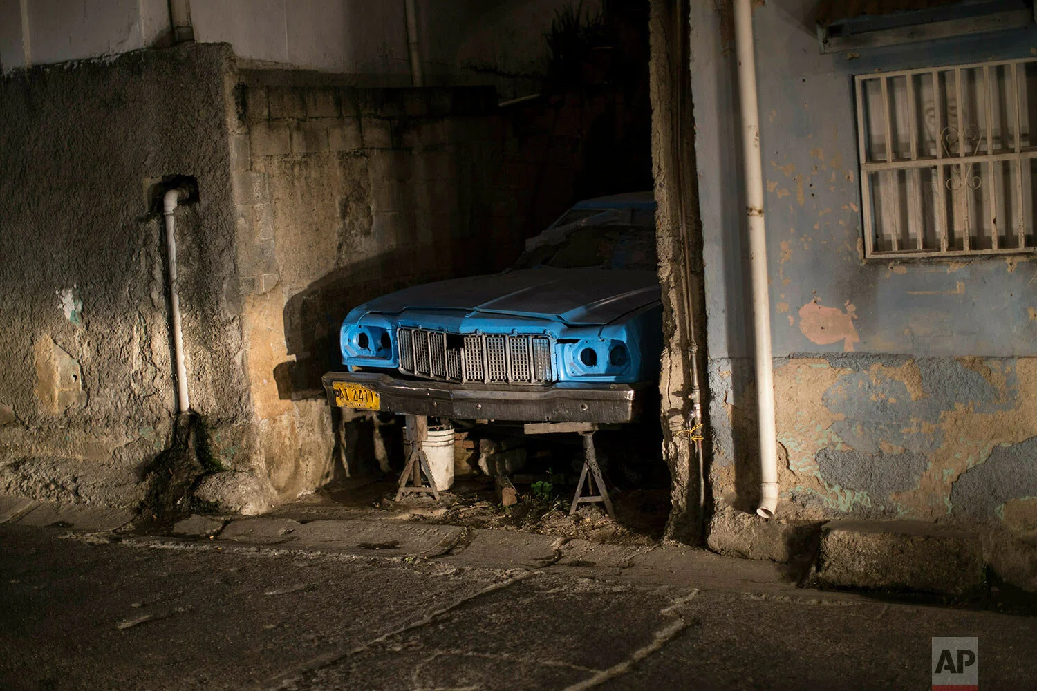 A car being repaired stands on stilts in the Catia district of Caracas, Venezuela, Thursday, Jan. 31, 2019. An independent U.N. human rights monitor says economic sanctions are compounding a "grave crisis" in Venezuela. (AP Photo/Rodrigo Abd)