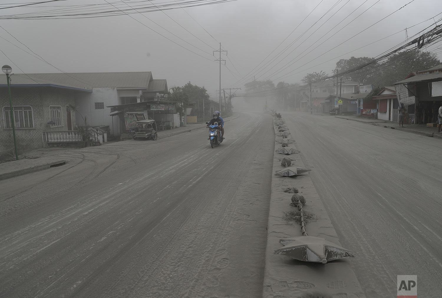  A man negotiates a road covered with ash spewed from Taal Volcano in Lemery, Batangas, southern Philippines on Monday Jan. 13, 2020.  (AP Photo/Aaron Favila) 