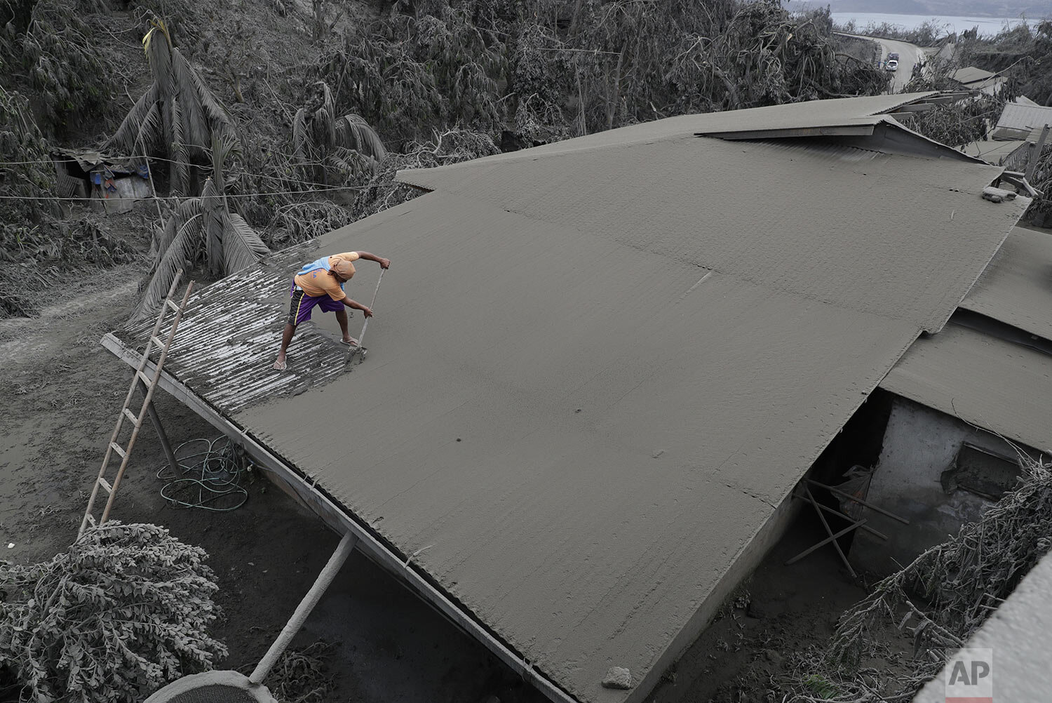  A resident clears volcanic ash from his roof in Laurel, Batangas province, southern Philippines on Tuesday, Jan. 14, 2020. (AP Photo/Aaron Favila) 