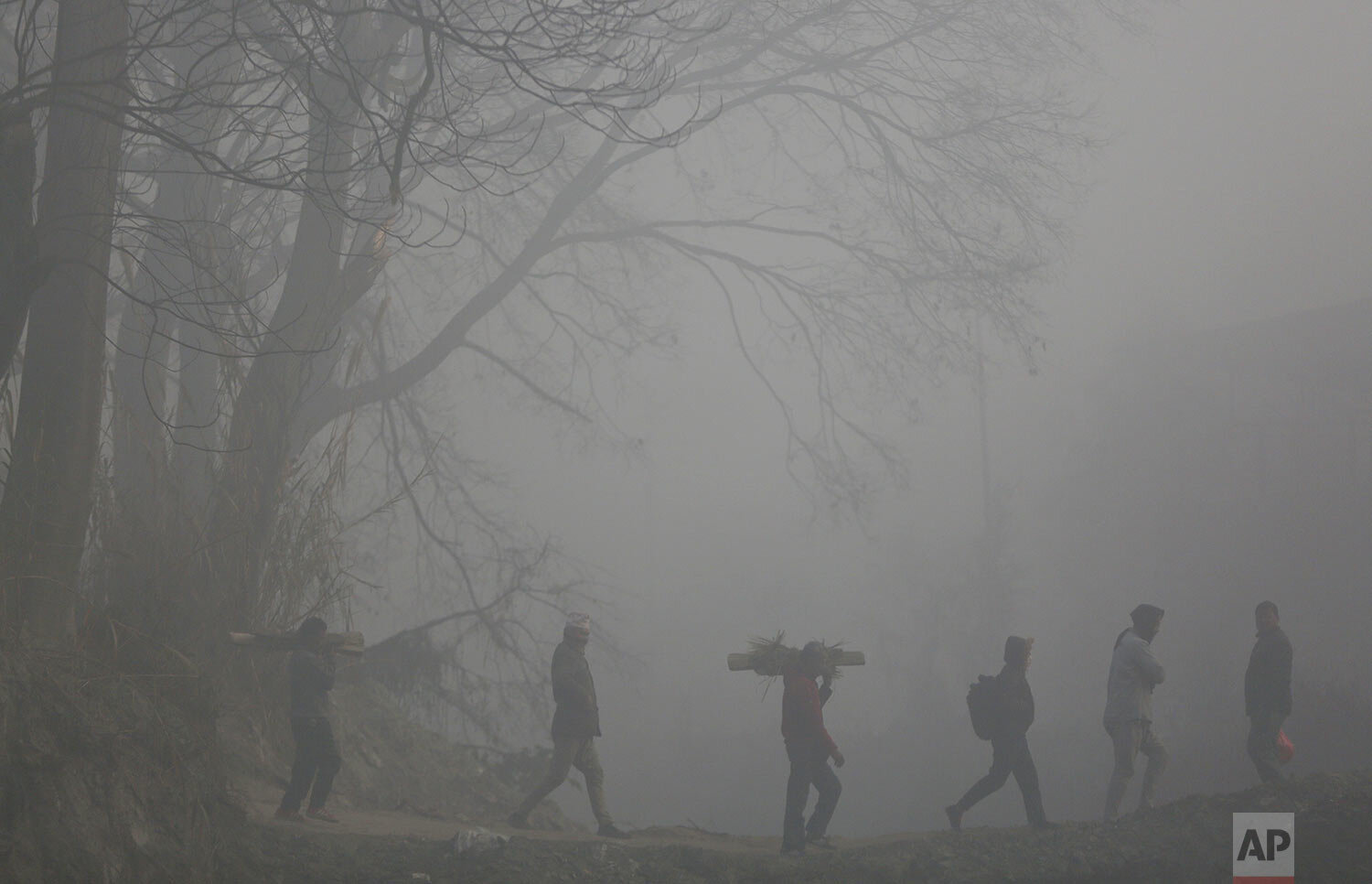  Nepalese men carry logs of wood for a cremation, enveloped in thick morning fog in Bhaktapur, Nepal, Wednesday, Jan. 15, 2020. (AP Photo/Niranjan Shrestha) 