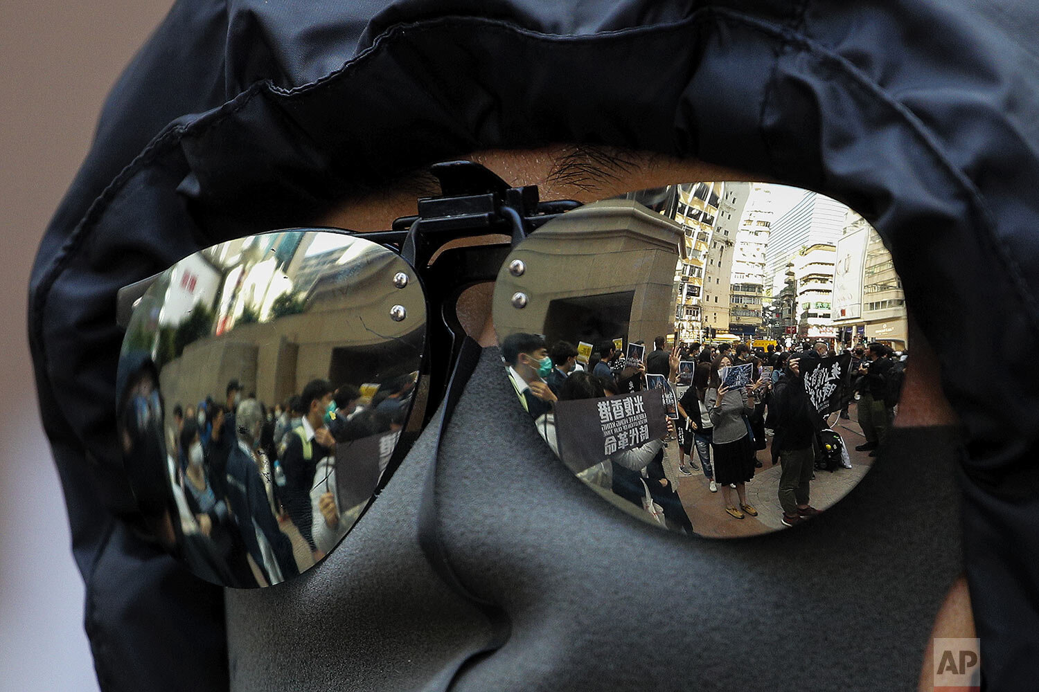  Pro-democracy demonstrators holding placards are reflected on a protester's sunglasses during a rally outside the Times Square shopping mall at Causeway Bay in Hong Kong, Monday, Jan. 6, 2020.  (AP Photo/Andy Wong) 