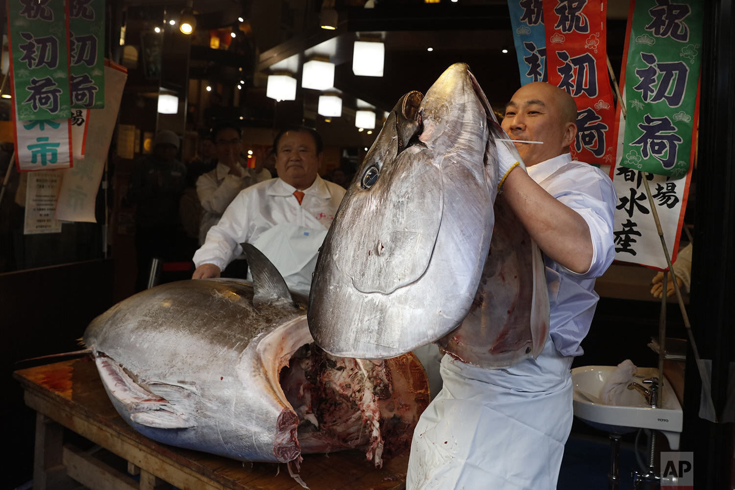  A sushi chef holds up the head of a bluefin tuna at a restaurant in Tsukji market area in Tokyo, after it was sold at the first auction of 2020 at Tokyo's Toyosu fish market, Sunday, Jan. 5, 2020. (AP Photo/Jae C. Hong) 