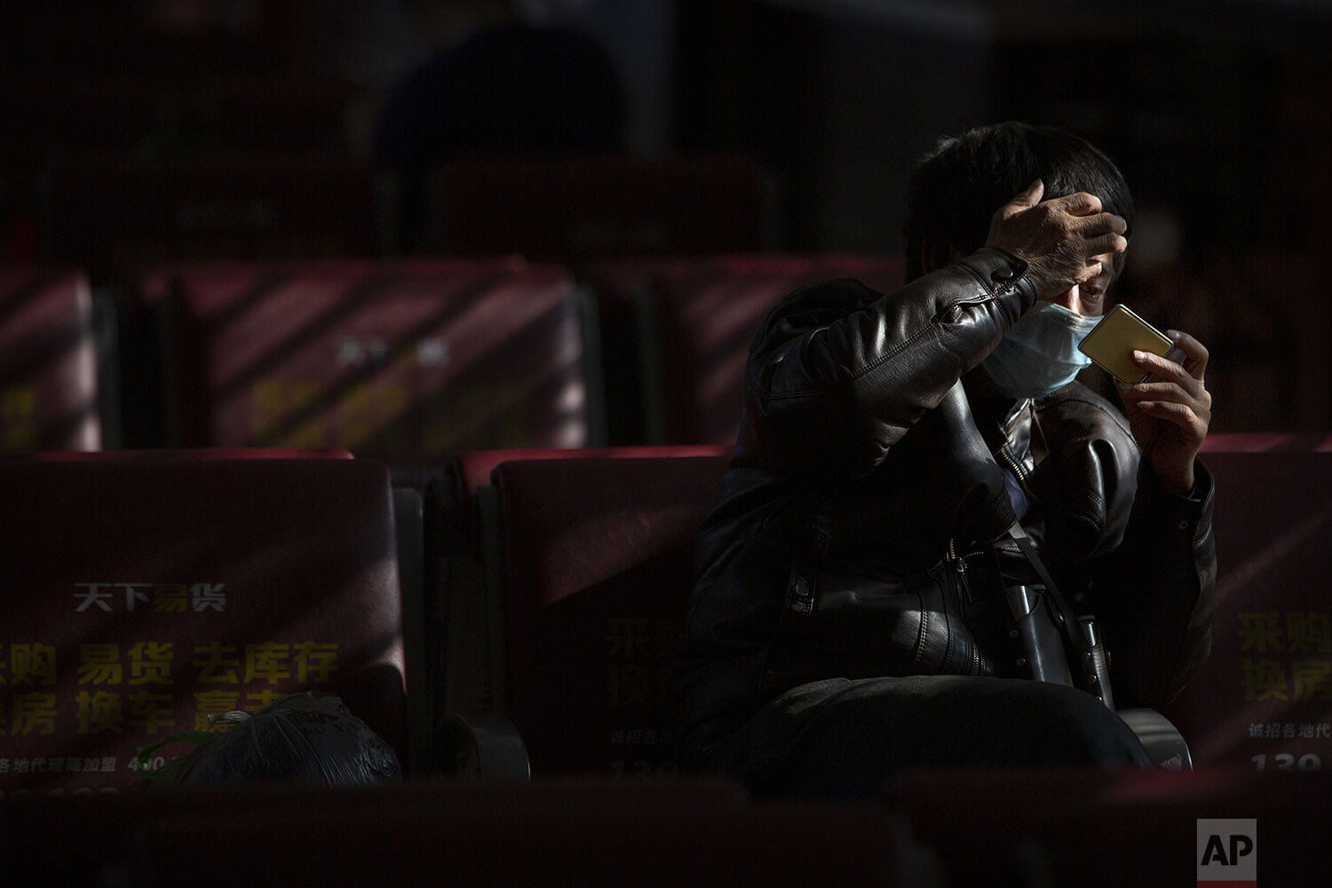  A traveler wears a face mask as he waits for a train at the Beijing Railway Station in Beijing, Friday, Jan. 31, 2020. (AP Photo/Mark Schiefelbein) 