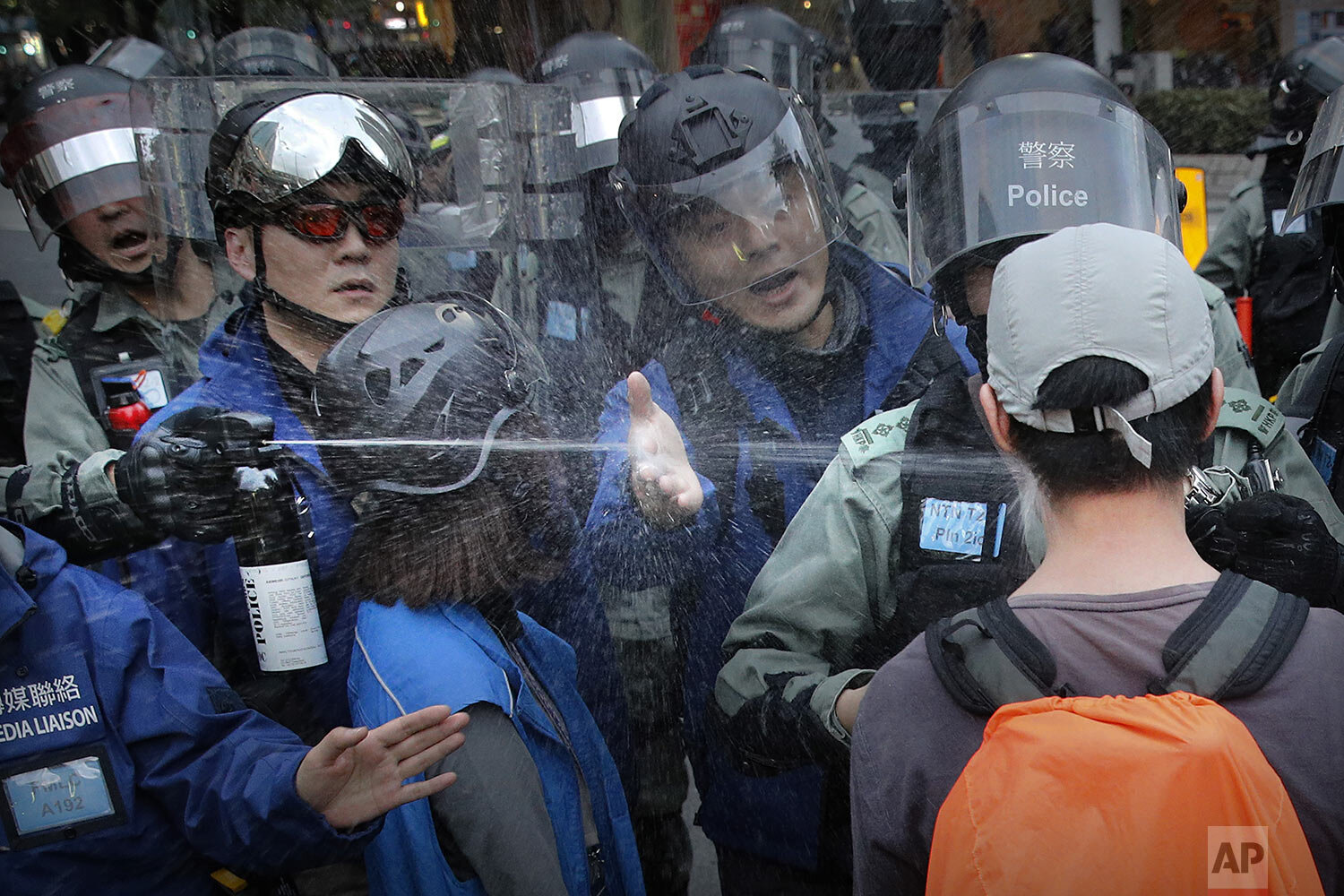  A riot policeman sprays pepper spray at a man as they disperse a crowd during a demonstration against "parallel traders" who buy goods in Hong Kong to resell in mainland China in Sheung Shui near the Chinese border in Hong Kong, Sunday, Jan. 5, 2020