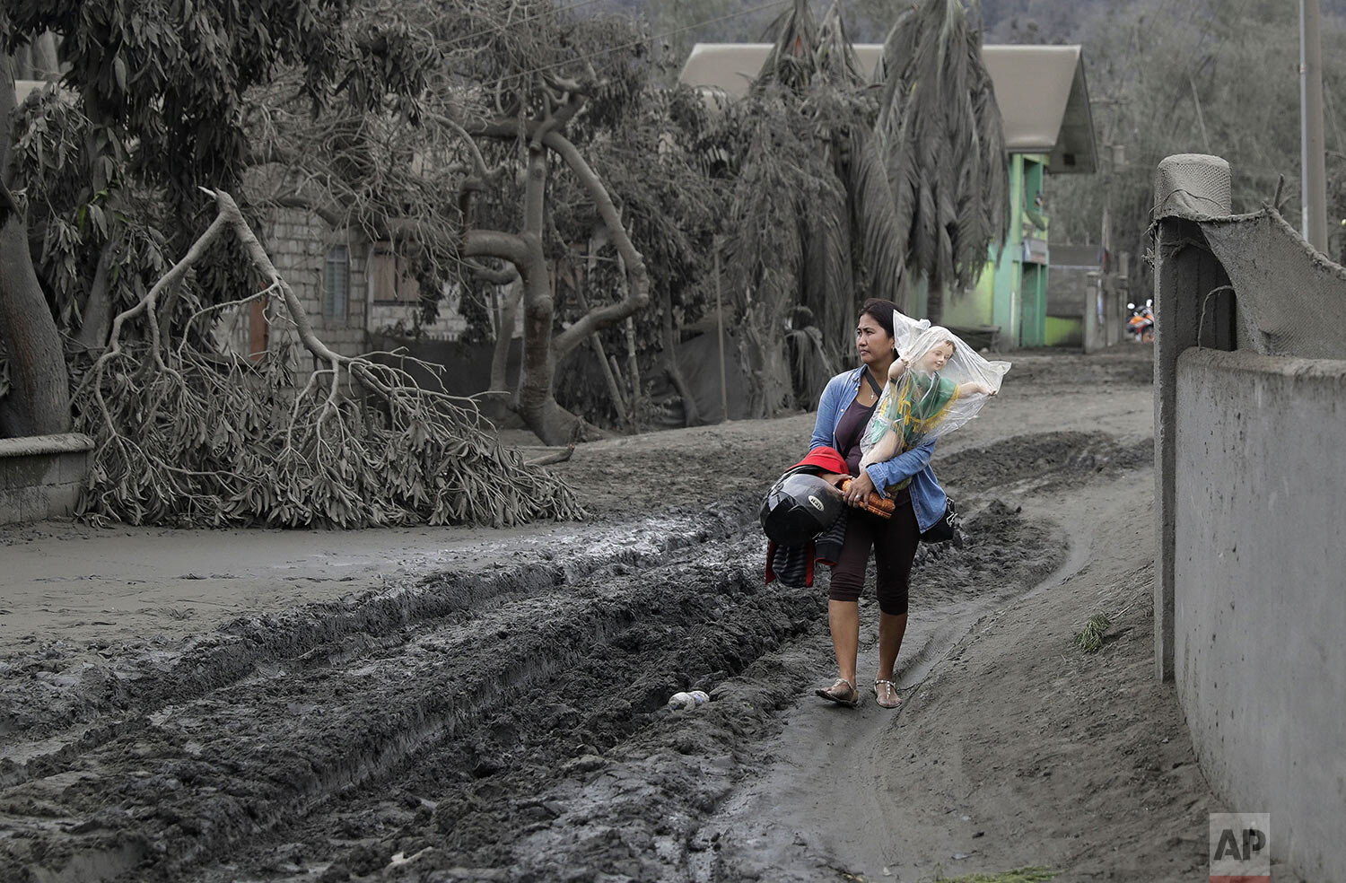  Leila de Castro carries a statue of the baby Jesus which she recovered from the house of her sister as she walks on a road covered with volcanic ash in Boso-Boso, Batangas province, southern Philippines, Tuesday, Jan. 14, 2020. (AP Photo/Aaron Favil