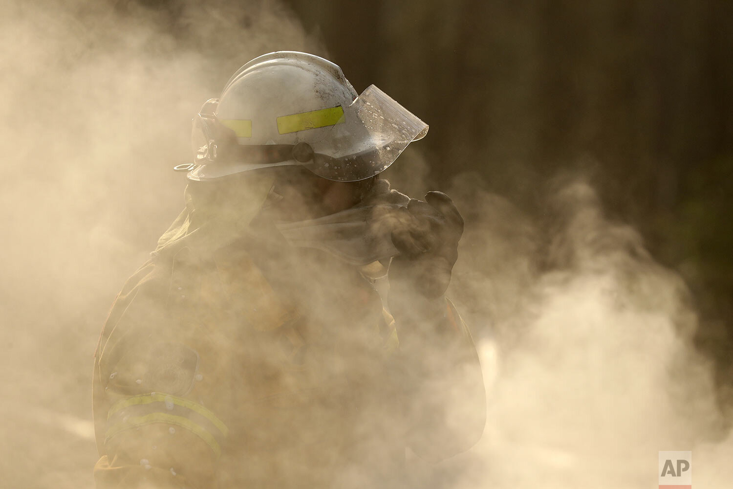  A firefighter covers his face from block smoke as he battles a fire near Bendalong, Australia, Friday, Jan. 3, 2020. (AP Photo/Rick Rycroft) 