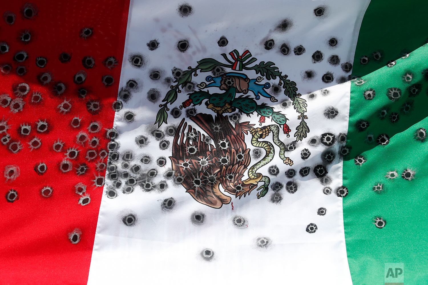  An upside-down Mexican flag, modified to look like it is riven with bullet holes, is carried by members of the LeBaron family during a march against violence called "Walk for Peace," on the road between Tres Marias and Mexico City, Friday, Jan. 24, 