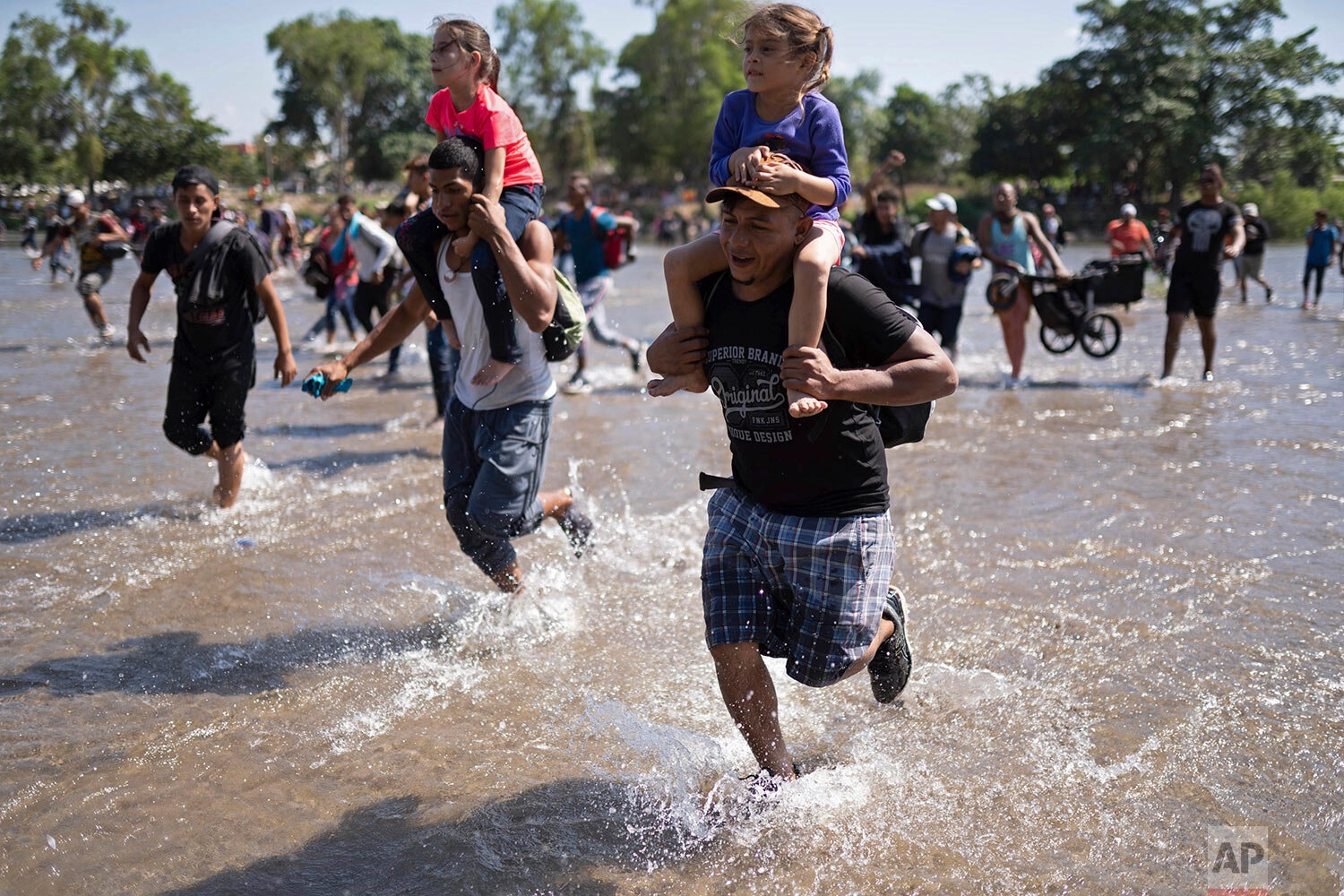  Central American migrants carry children as they run across the Suchiate River from Guatemala to Mexico, near Ciudad Hidalgo, Mexico, Monday, Jan. 20, 2020. (AP Photo/Santiago Billy) 