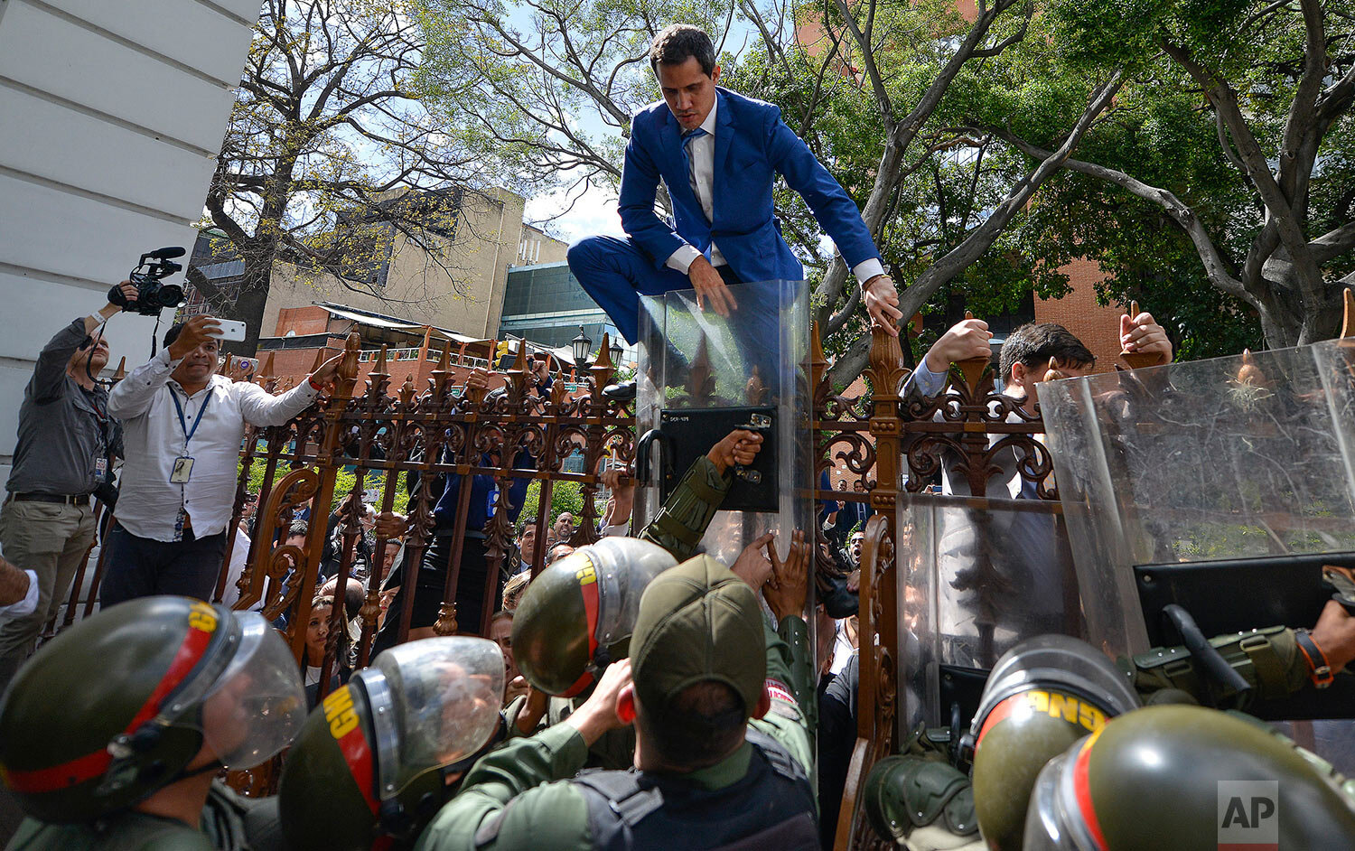  National Assembly President Juan Guaido, Venezuela's opposition leader, climbs the fence in a failed attempt to enter the compound of the Assembly, as he and other opposition lawmakers are blocked from entering a session to elect new Assembly leader