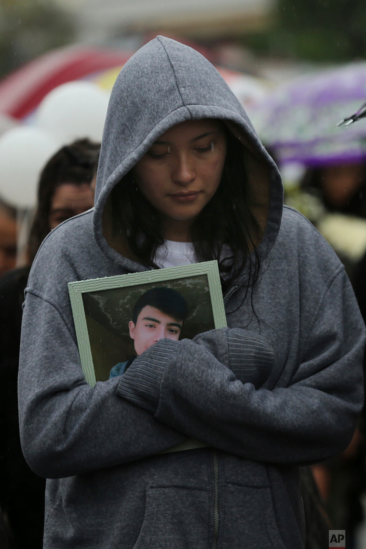  A woman takes part in funeral procession holding a framed photo of one of the victims of a shooting at a video-game arcade, in Uruapan, Mexico, Wednesday, Feb. 5, 2020. (AP Photo/Marco Ugarte) 