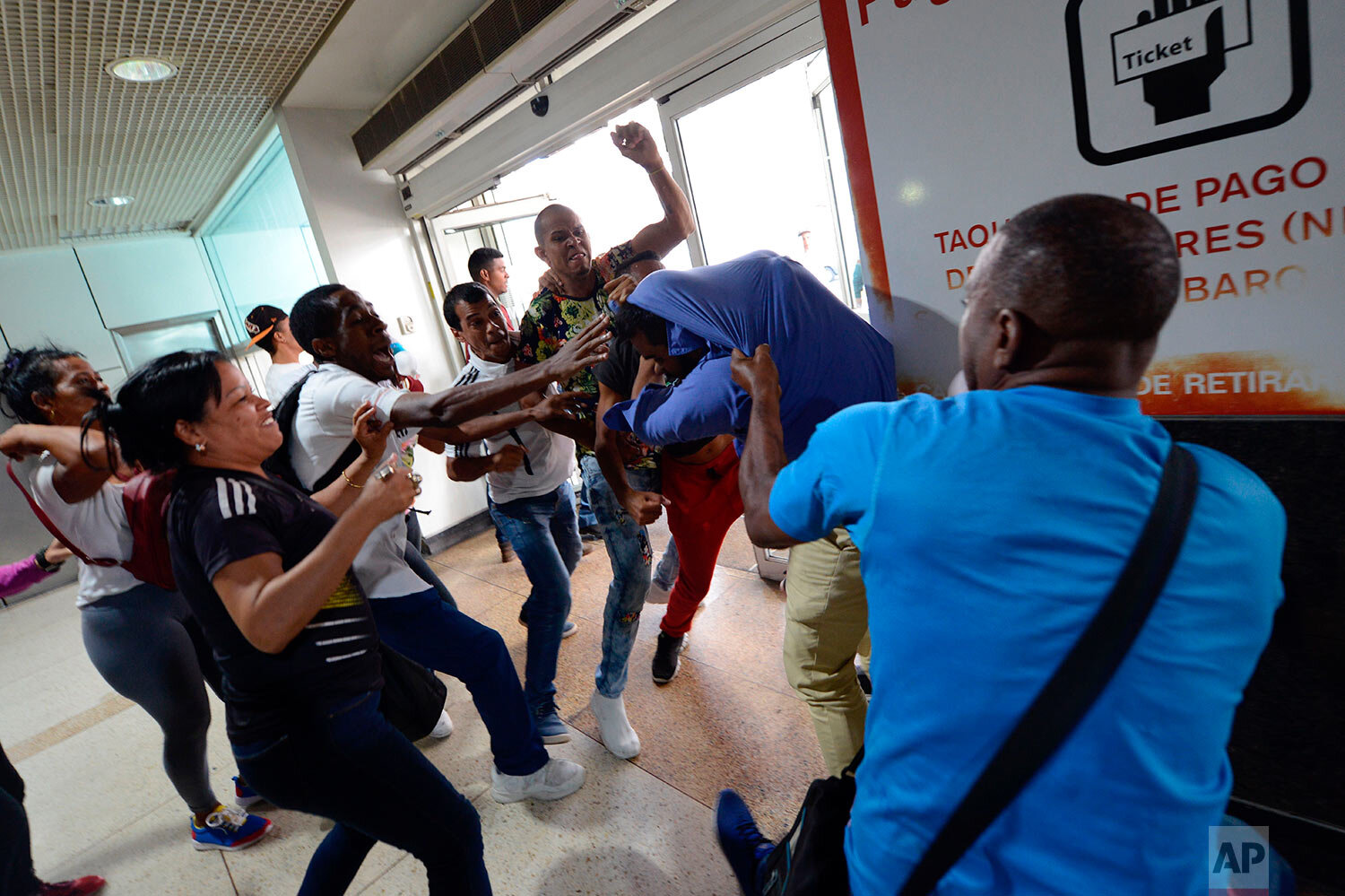  Government supporters, left and front, fight with a member of the opposition who is awaiting the arrival of opposition leader Juan Guaido at the Simon Bolivar International Airport in La Guaira, Venezuela, Tuesday, Feb. 11, 2020. (AP Photo/Matias De