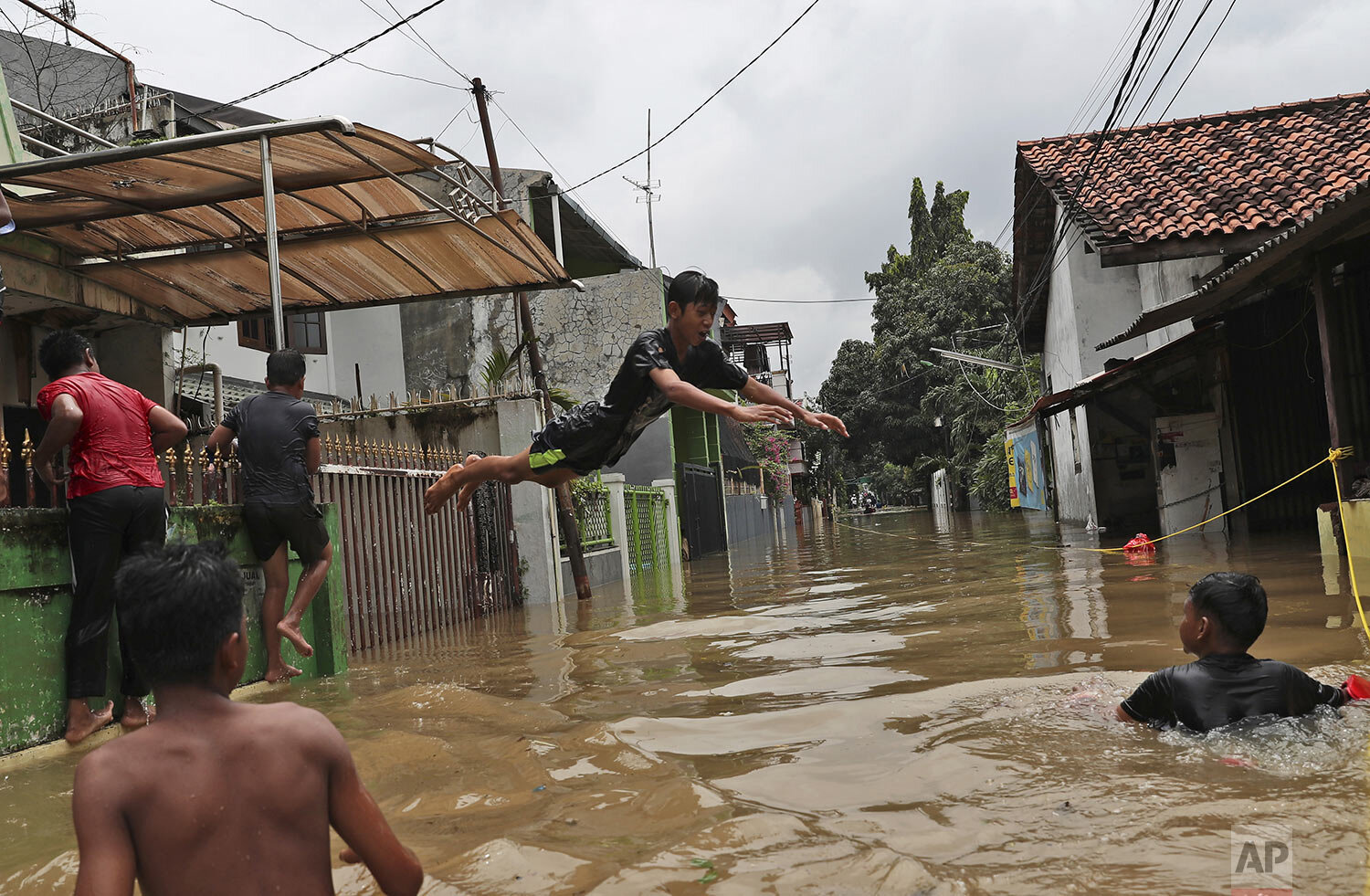 Indonesian youths play in flood water in a neighborhood in Jakarta, Indonesia, Tuesday, Feb. 25, 2020. (AP Photo/Achmad Ibrahim)