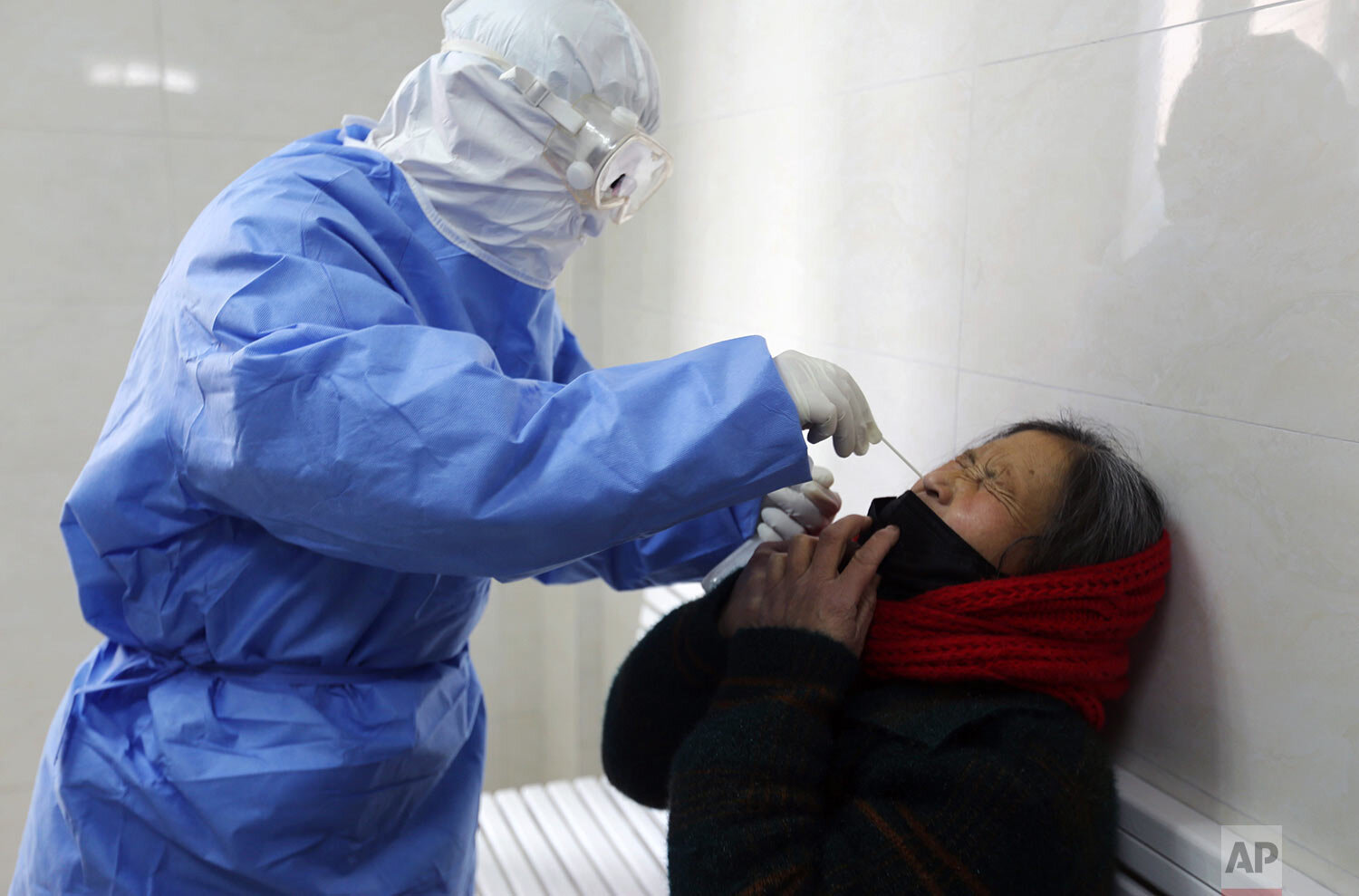 A doctor takes a swab from a woman to test for the COVID-19 virus at a fever clinic in Yinan county in eastern China's Shandong province Wednesday, Feb. 12, 2020. (Chinatopix Via AP)