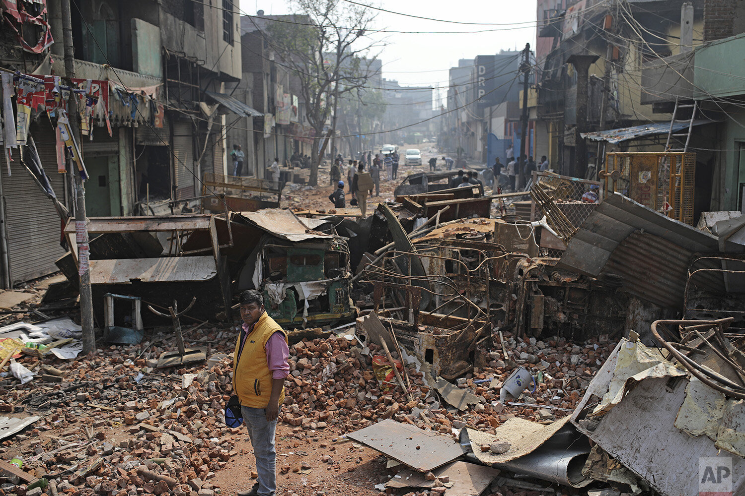  A Delhi municipal worker stands next to heaps of the remains of vehicle, steel cupboards and other materials on a street vandalized in Tuesday's violence in New Delhi, India, Thursday, Feb. 27, 2020. India accused a U.S. government commission of pol