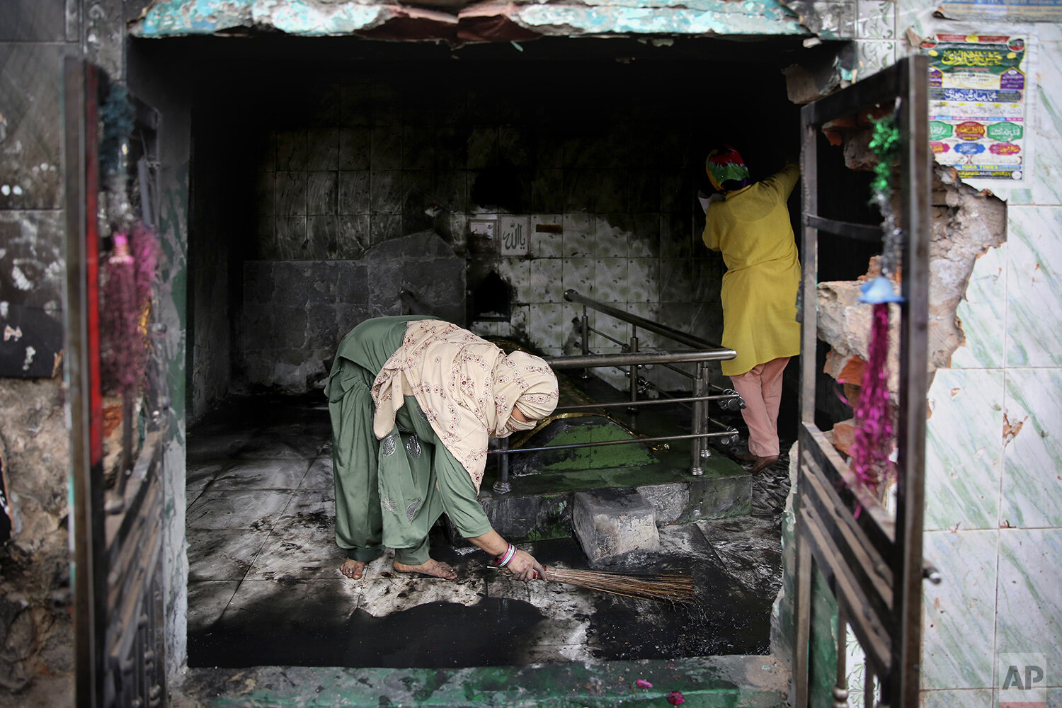  Muslim women clean a shrine burnt by a Hindu mob in Tuesday's violence in New Delhi, India, Thursday, Feb. 27, 2020. India accused a U.S. government commission of politicizing communal violence in New Delhi that killed at least 30 people and injured
