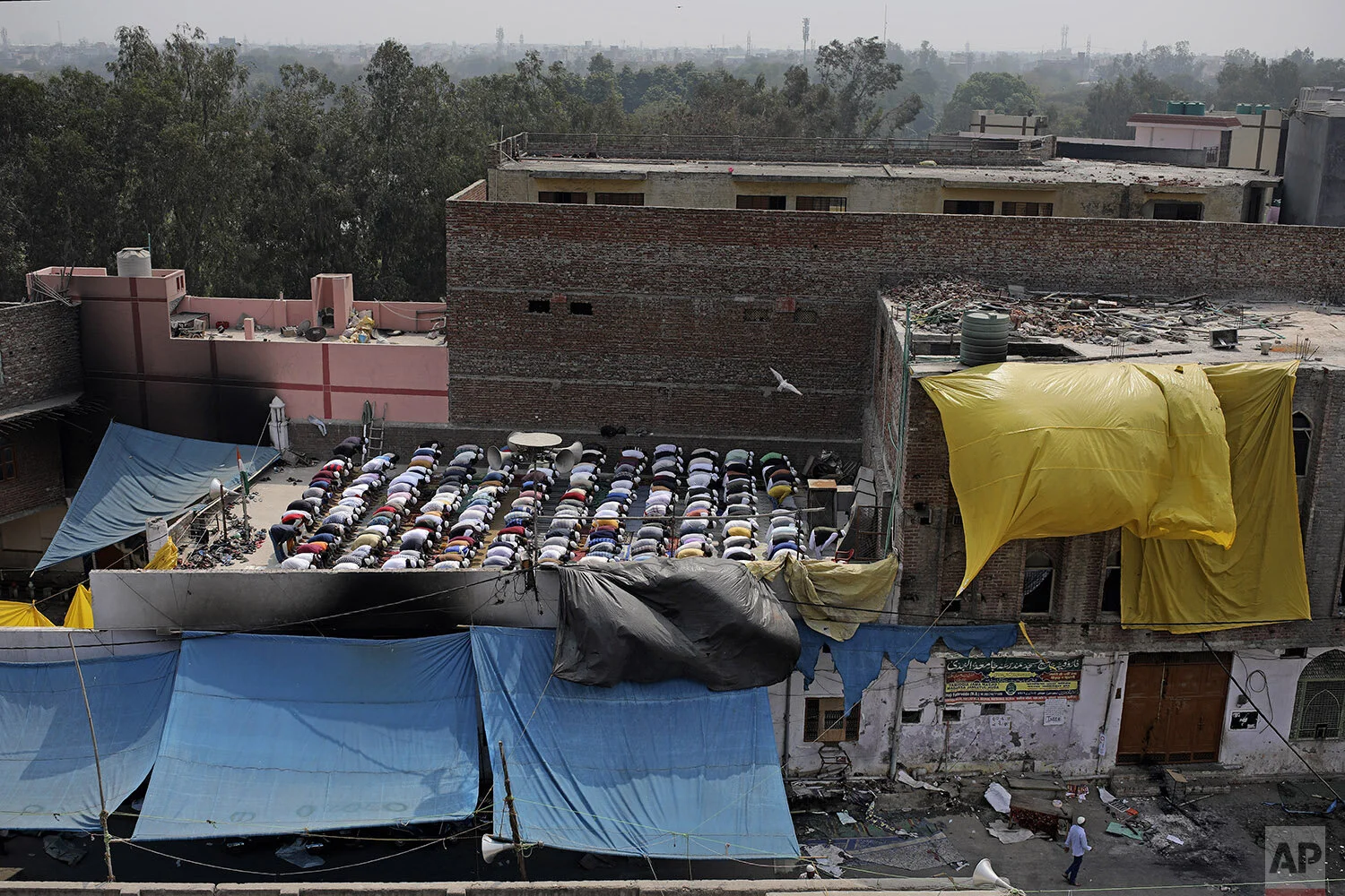 Muslims offer prayers on the roof of a fire-bombed mosque in New Delhi, India, Friday, Feb. 28, 2020. Muslims returned to the battle-torn streets of northeastern New Delhi for weekly prayers at heavily-policed fire-bombed mosques on Friday, two days