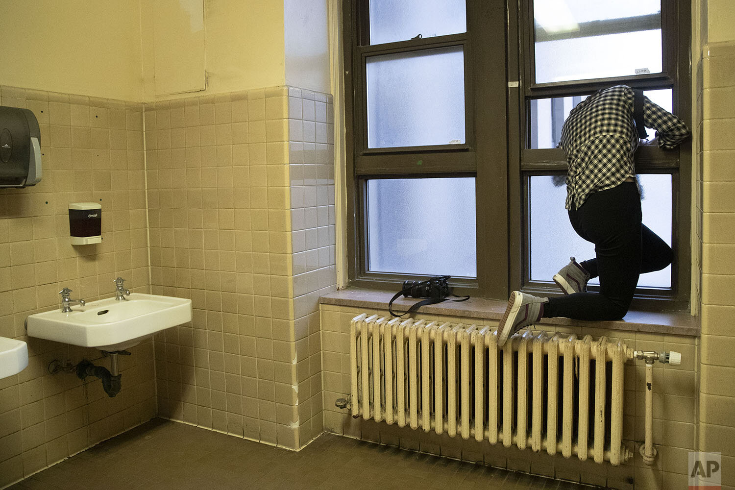  Freelance photographer working for Reuters Caitlin Ochs uses a window in a women’s restroom to shoot an overhead photo of Harvey Weinstein leaving the courthouse for the day during his rape trial, Tuesday, Feb. 18, 2020, in New York. (AP Photo/Mary 