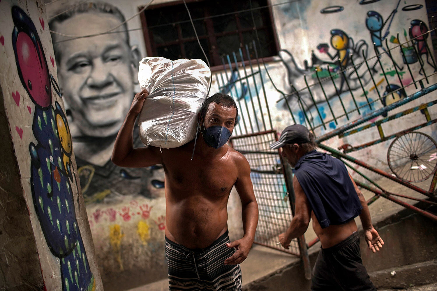  A man carries a bag as he uses a face mask as a precaution against the spread of the new coronavirus in the Rocinha slum of Rio de Janeiro, Brazil, March 20, 2020. (AP Photo/Silvia Izquierdo) 
