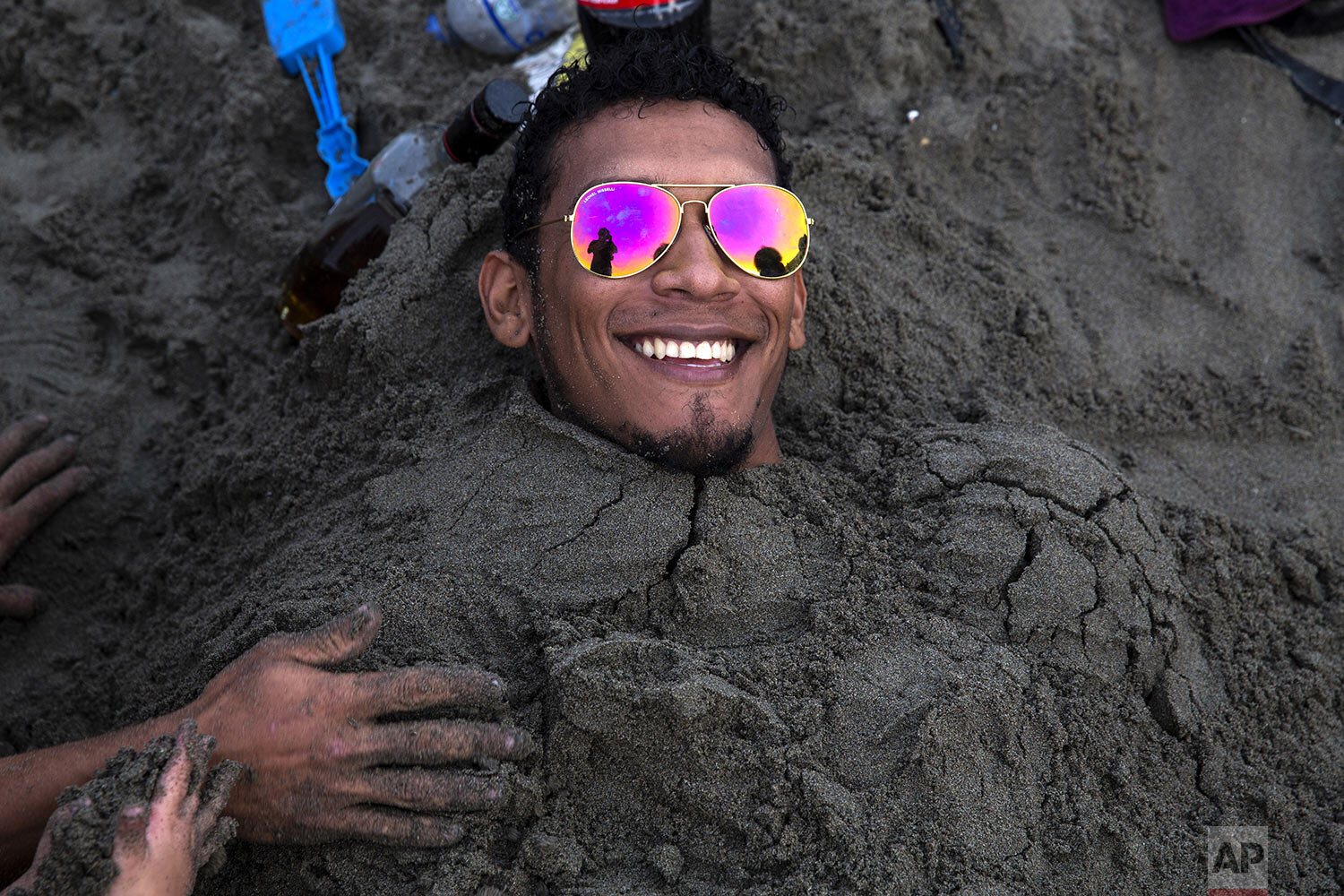  A man smiles as he buried in the sand on a day out with friends on Agua Dulce beach in Lima, Peru, Feb. 16, 2020. (AP Photo/Rodrigo Abd) 