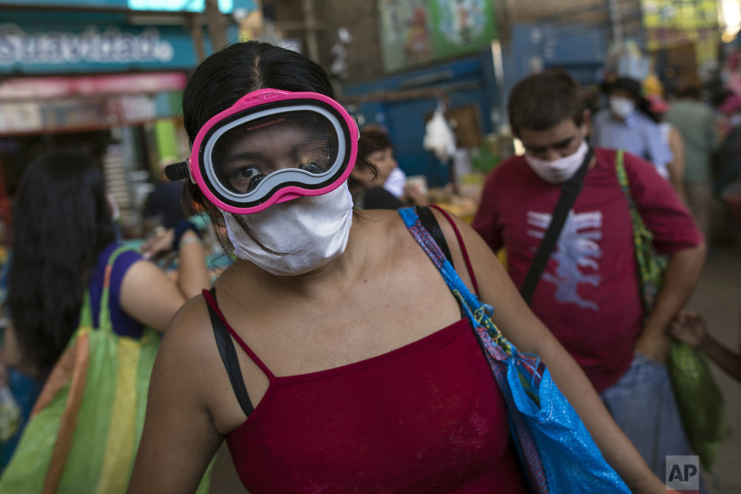  A woman wears a snorkel mask and a surgical face mask as a precaution amid the spread of the new coronavirus while shopping at a market in Lima, Peru, March 23, 2020. (AP Photo/Rodrigo Abd) 