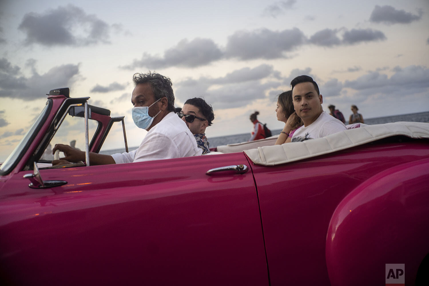  A taxi driver, wearing a protective mask as a precaution against the spread of the new coronavirus, drives his American classic car with tourists in Havana, Cuba, March 13, 2020. (AP Photo / Ramon Espinosa) 