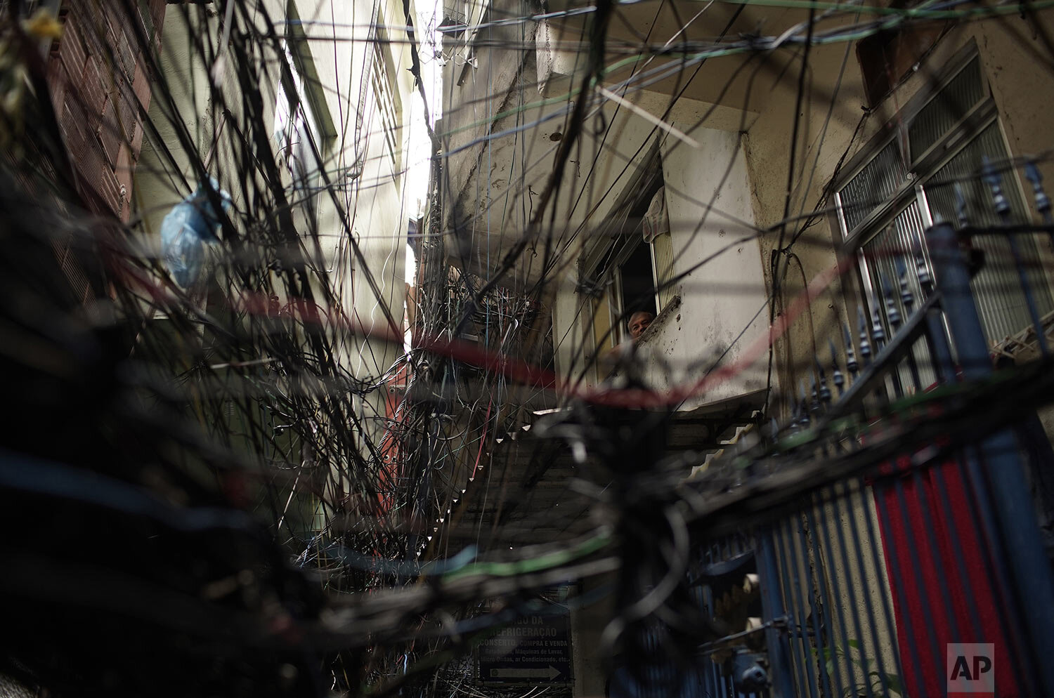  Seen through a web of electric wires, a senior citizen peers from his window in the Rocinha slum of Rio de Janeiro, Brazil, March 20, 2020, as many people stay indoors to avoid getting the new coronavirus. (AP Photo/Silvia Izquierdo) 