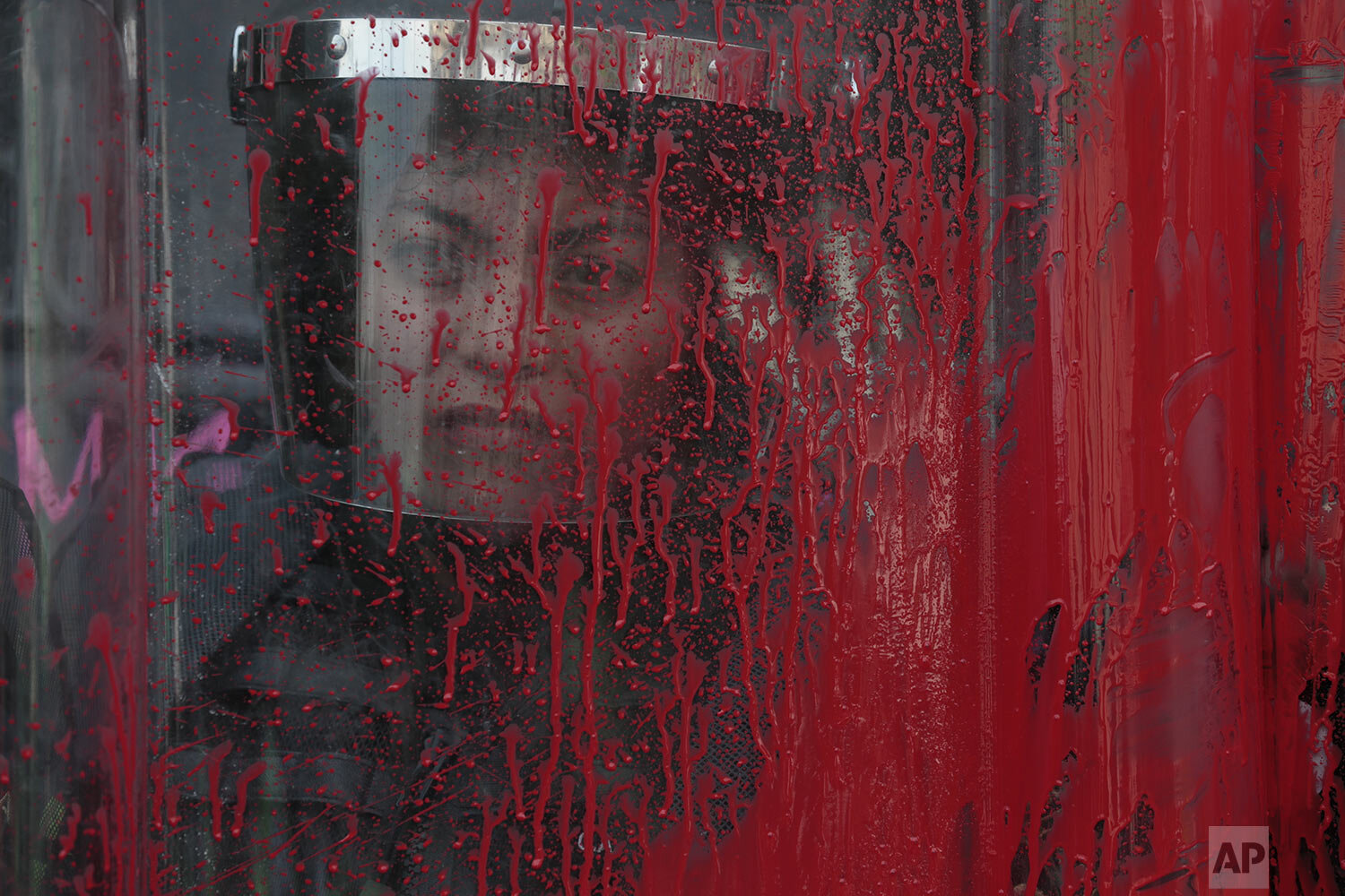  A police officer stands behind her riot shield covered in red paint during an International Women's Day march in Mexico City's main square, the Zocalo, March 8, 2020. Protests against gender violence in Mexico have intensified in recent years amid a