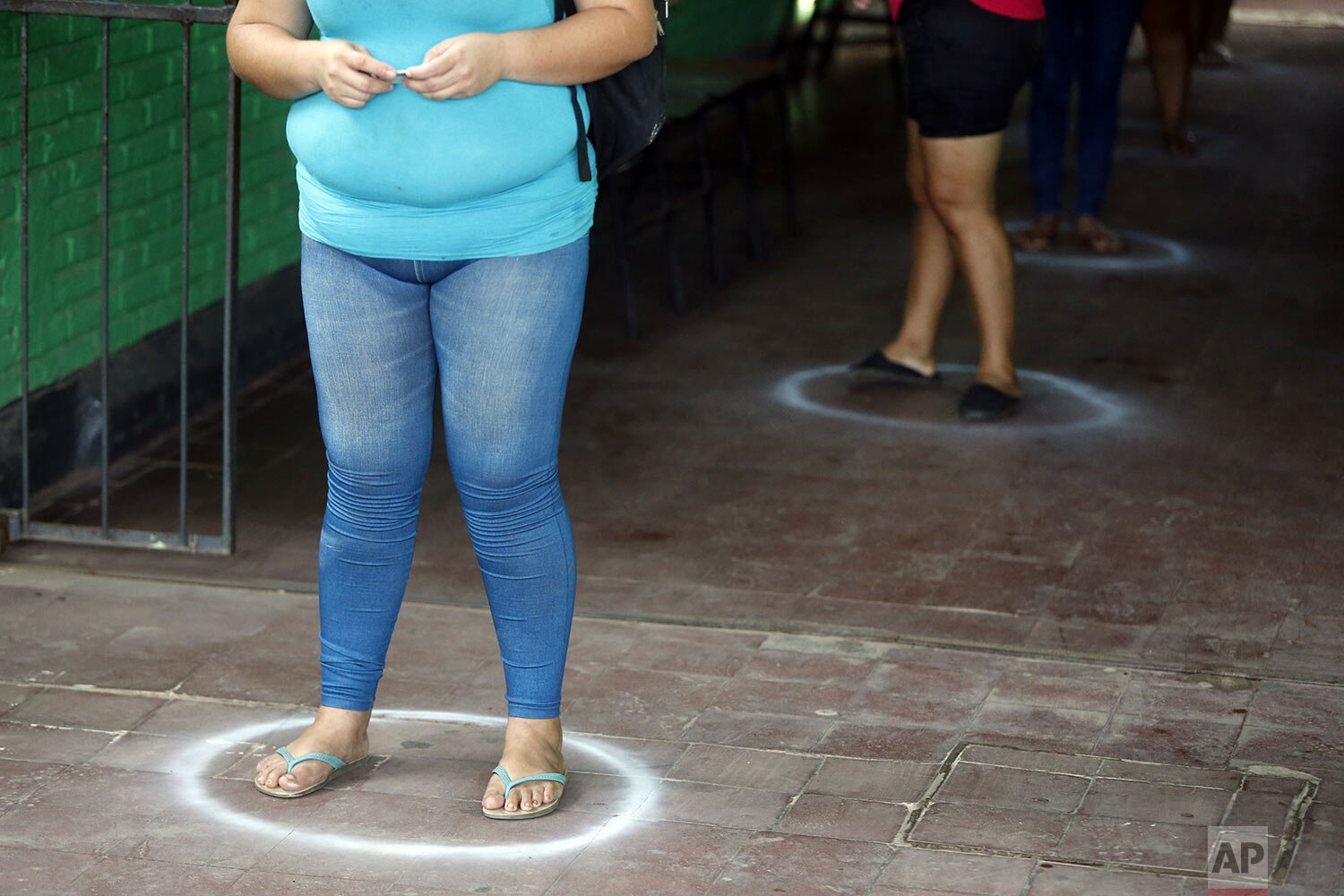  People stand in designated areas, to practice social distancing amid the spread of the new coronavirus, as they line up for free food staples at Santa Ana primary school in Asuncion, Paraguay, March 31, 2020, part of an already existing food program