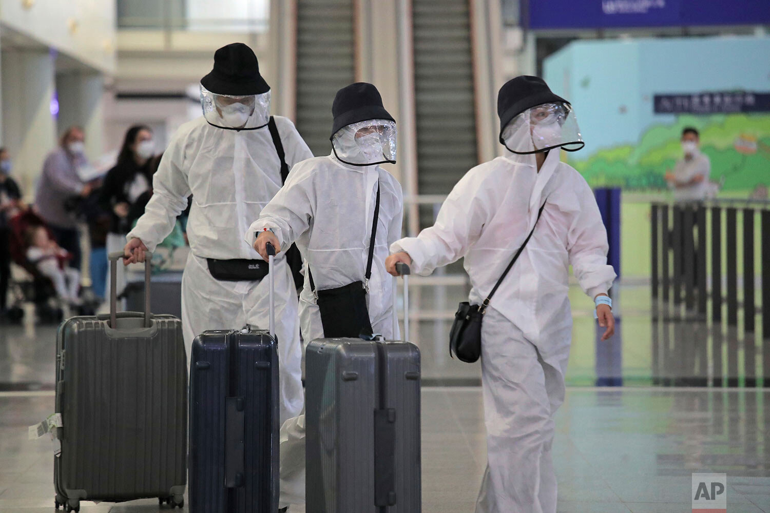  Passengers wear protective suits and face masks as they arrive at the Hong Kong airport, Monday, March 23, 2020.  (AP Photo/Kin Cheung) 