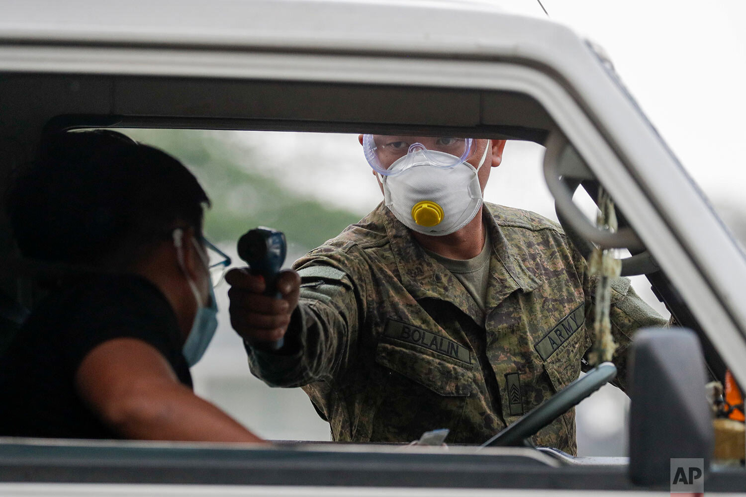  An army trooper uses a thermal scanner to check the temperature of people entering the metropolis at a checkpoint on the outskirts of Quezon city, Philippines, Sunday, March 15, 2020. (AP Photo/Aaron Favila) 