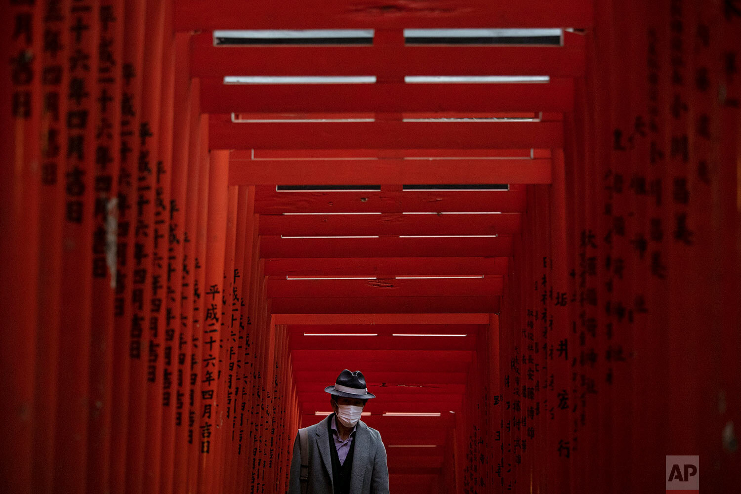  A man with a mask walks through torii gates at the Hie Shrine In Tokyo, Sunday, March 1, 2020.(AP Photo/Jae C. Hong) 
